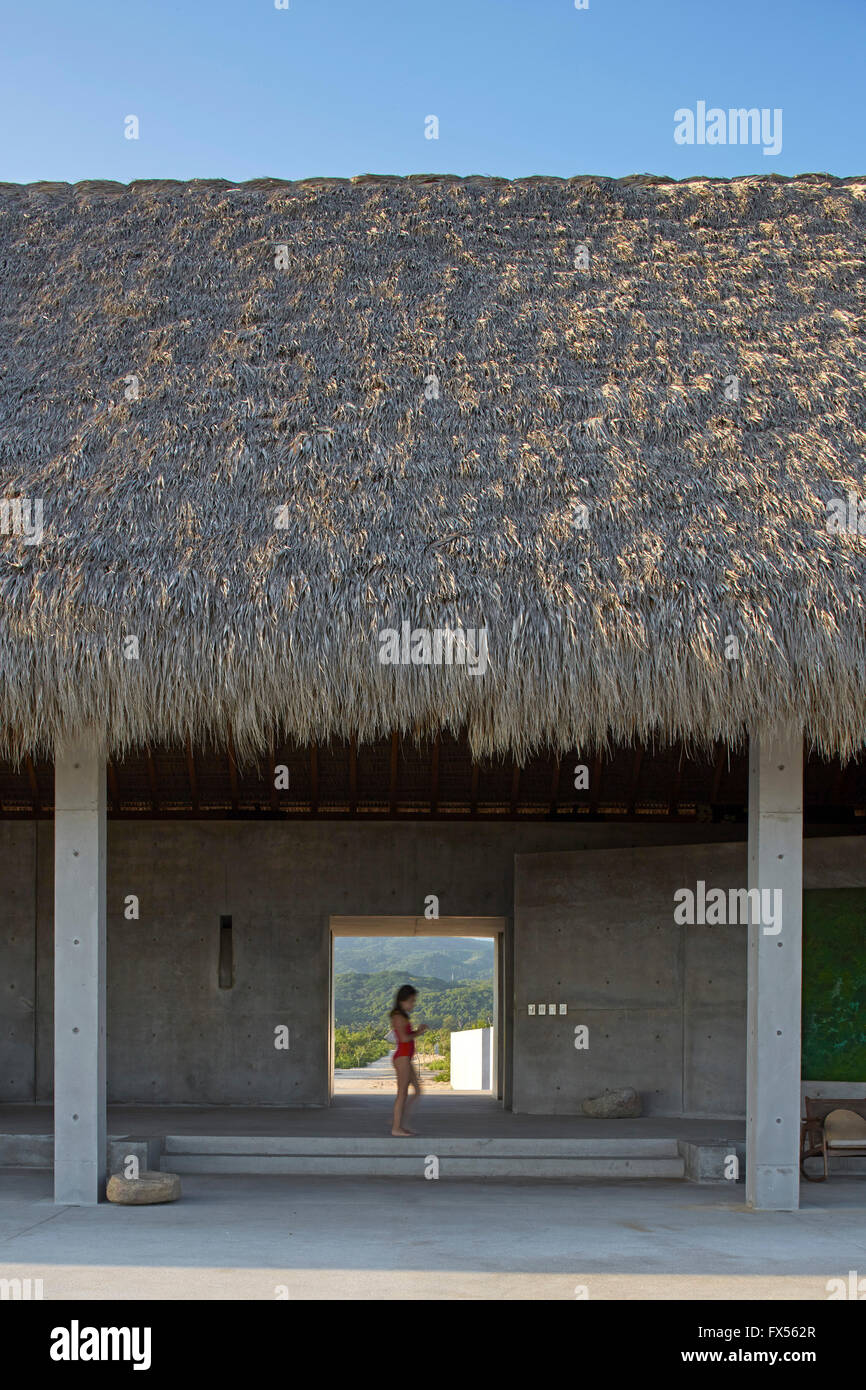 Ocean side view looking into main palapa with figure walking past entrance. Casa Wabi, Puerto Escondido, Mexico. Architect: Tada Stock Photo