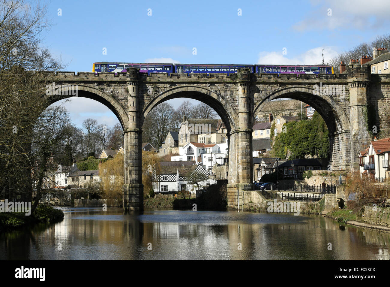 Sunshine hits a train as it crosses the River Nidd on the elegant viaduct in Knaresborough, North Yorkshire. Stock Photo