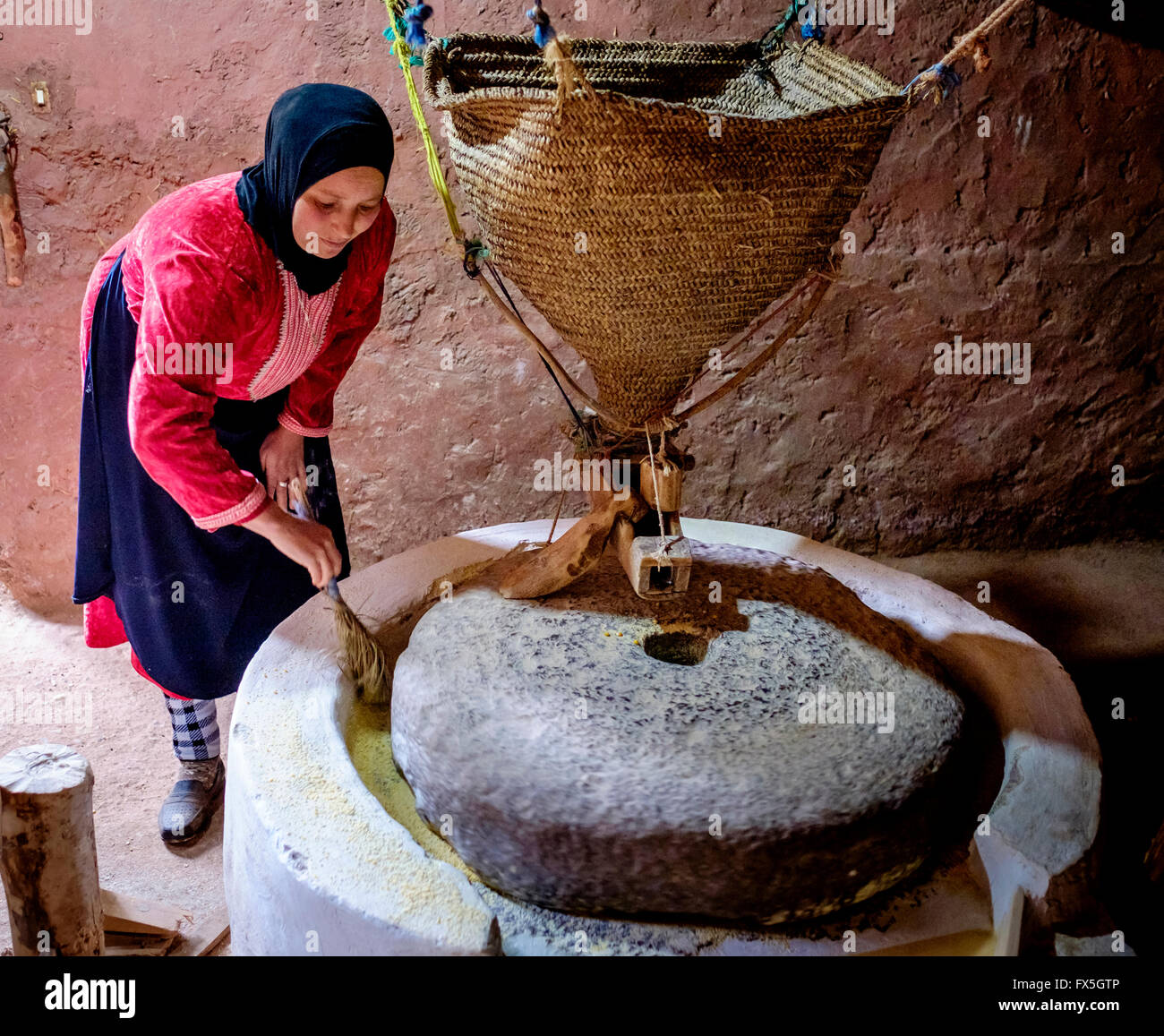 A Berber woman grinding corn to produce flour with a water driven stone