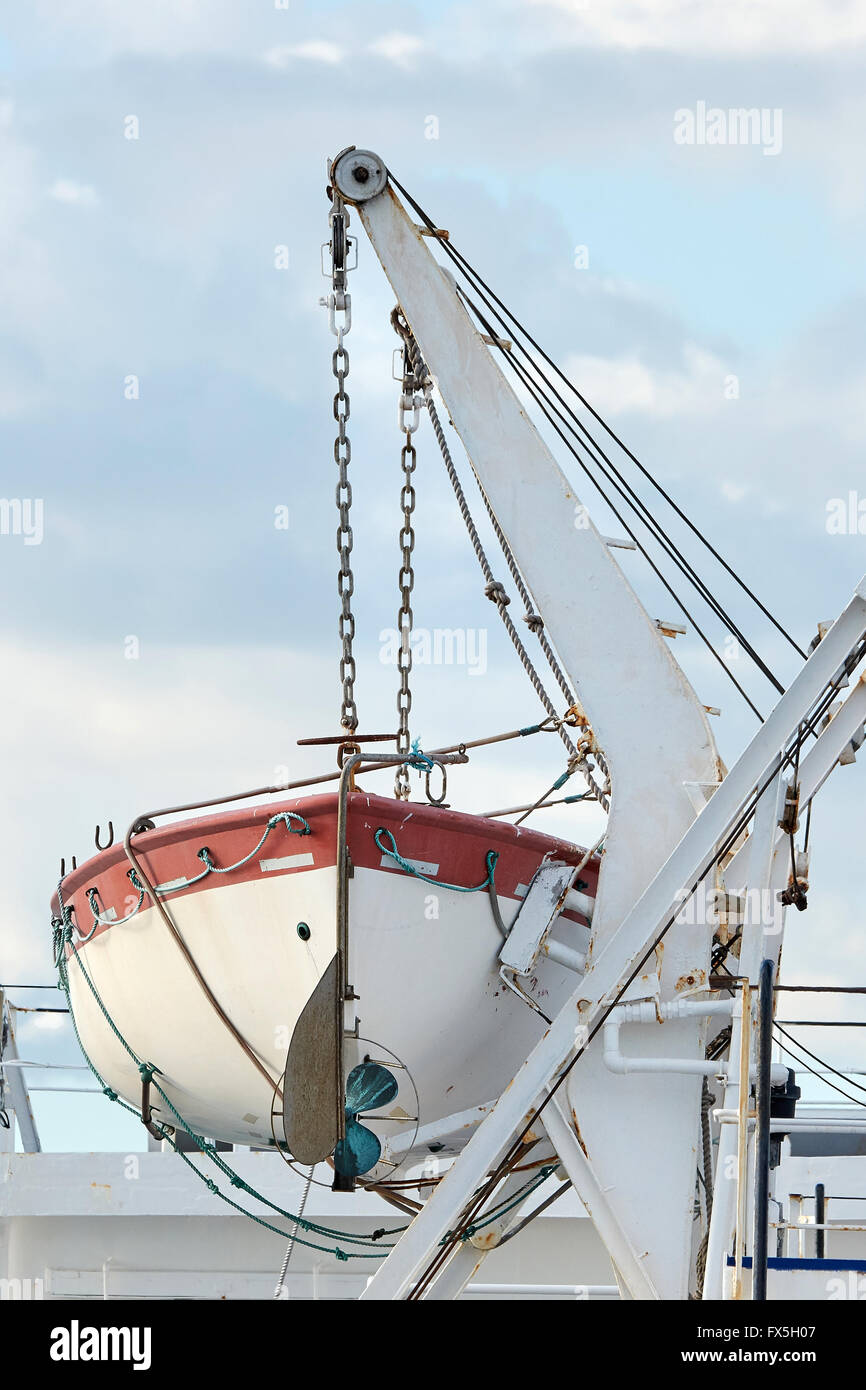 Lifeboat hanging in chains with blue skies in the background Stock Photo