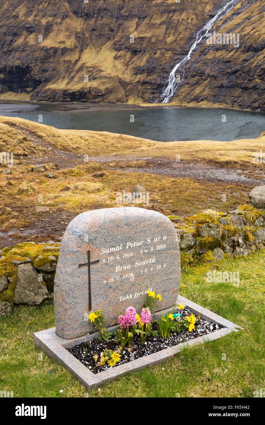 Headstone in church cemetery with waterfall at Saksun ancient village, Streymoy, Faroe Islands, Denmark in April Stock Photo