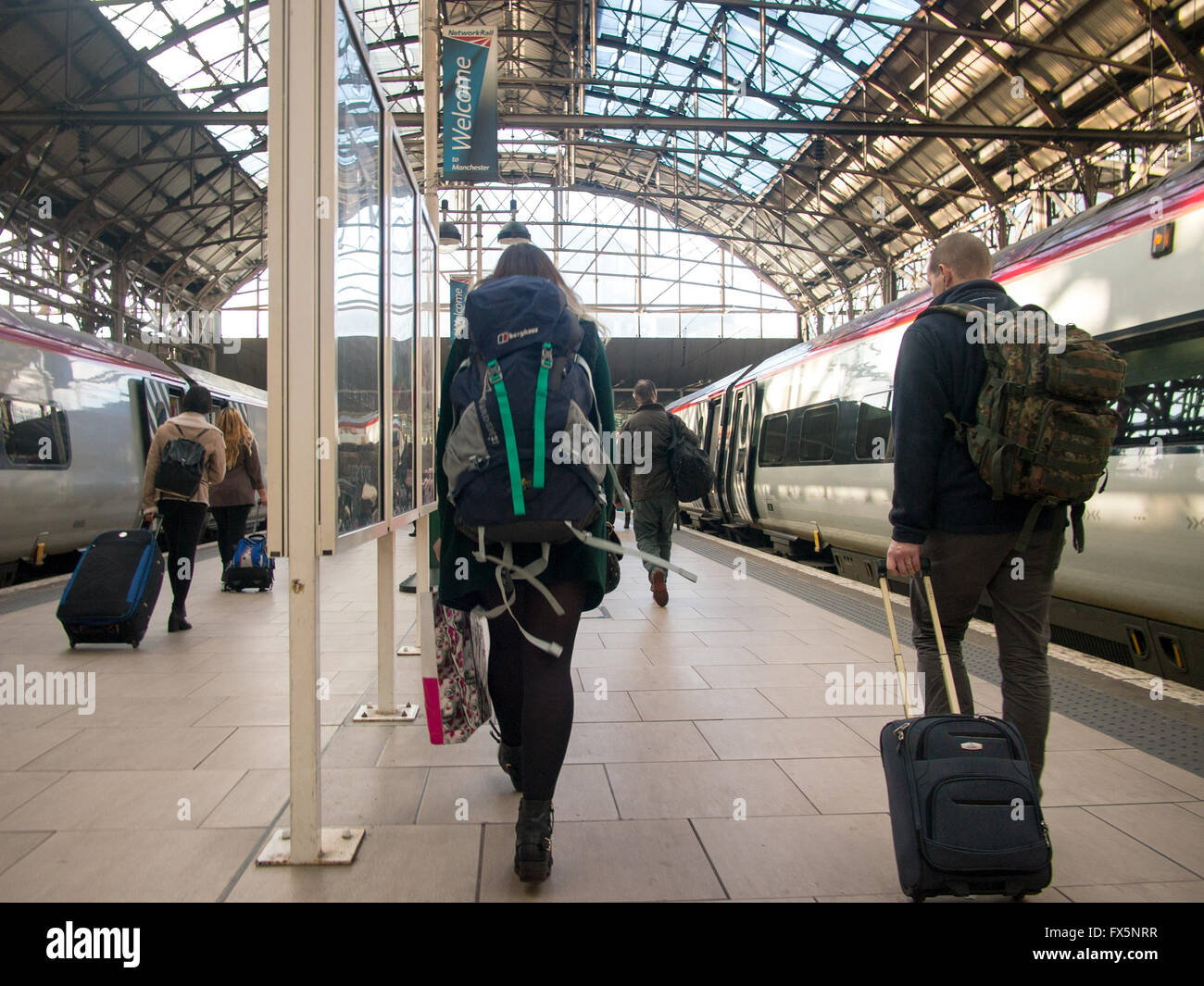 people carry bags along a train station platform after disembarking