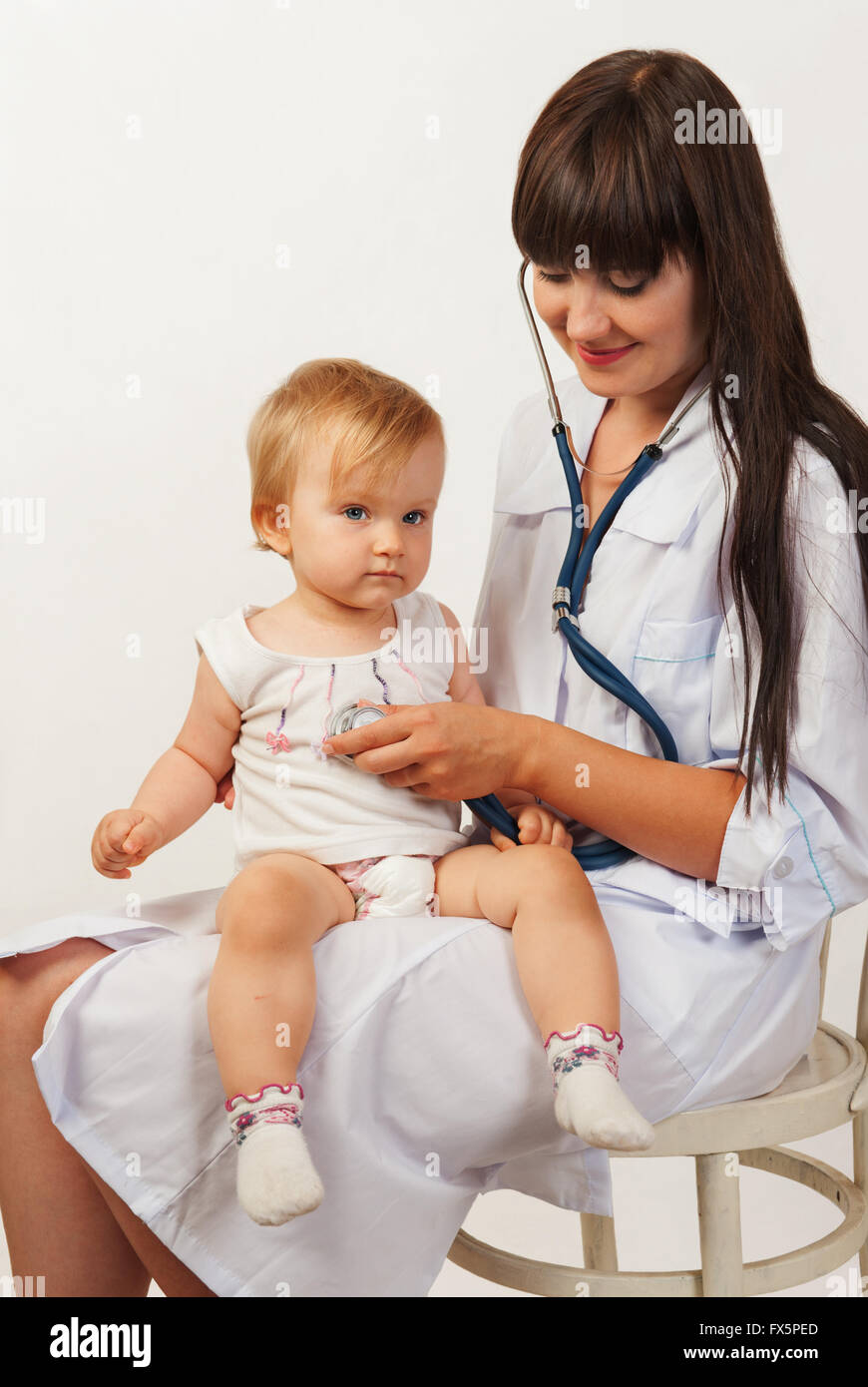 Pediatrician woman doctor with baby girl patient on light background Stock Photo