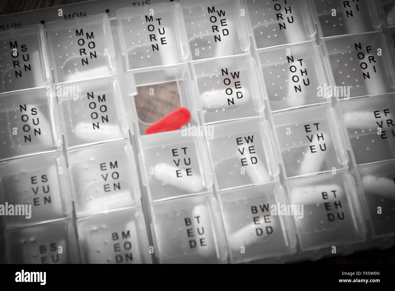 Daily pill box organiser with red pill Stock Photo