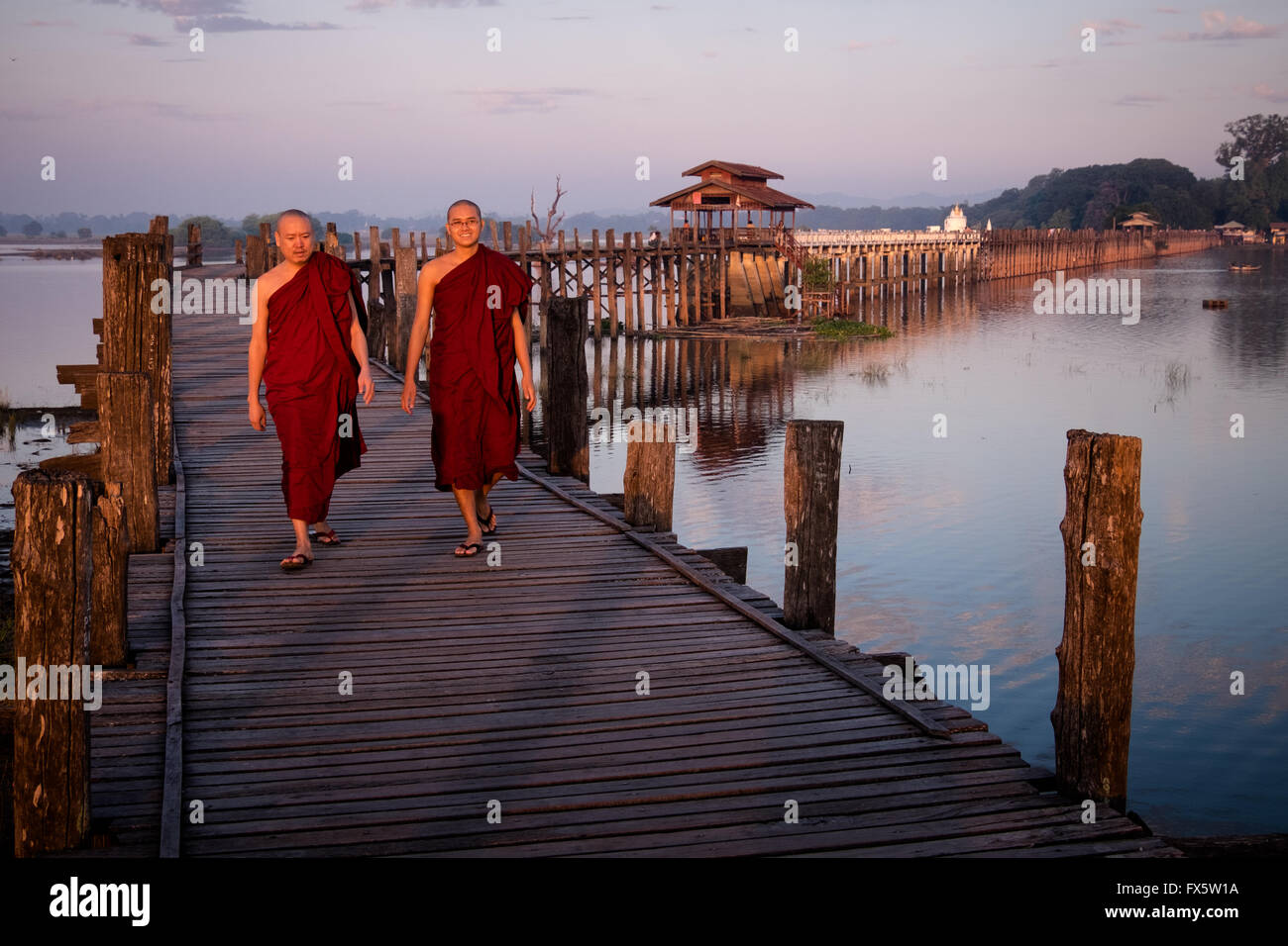 Two monks walk at sunrise across the wooden U Bein's Bridge near Amapura in Mandalay. Stock Photo