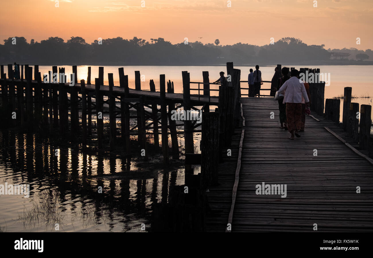 People across U Bein's Bridge near Amapura in Mandalay at sunrise Stock Photo