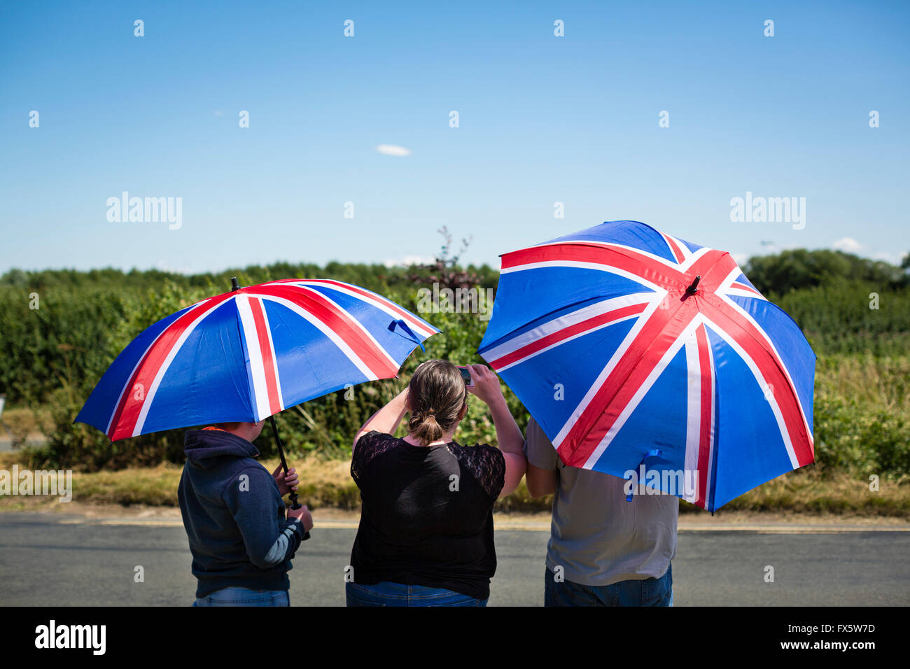 Plane spotters taking pictures of the old Avro Vulcan aircraft from underneath union jack umbrellas. Stock Photo