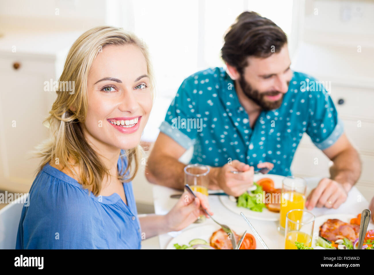 Beautiful young woman sitting at dining table smiling Stock Photo