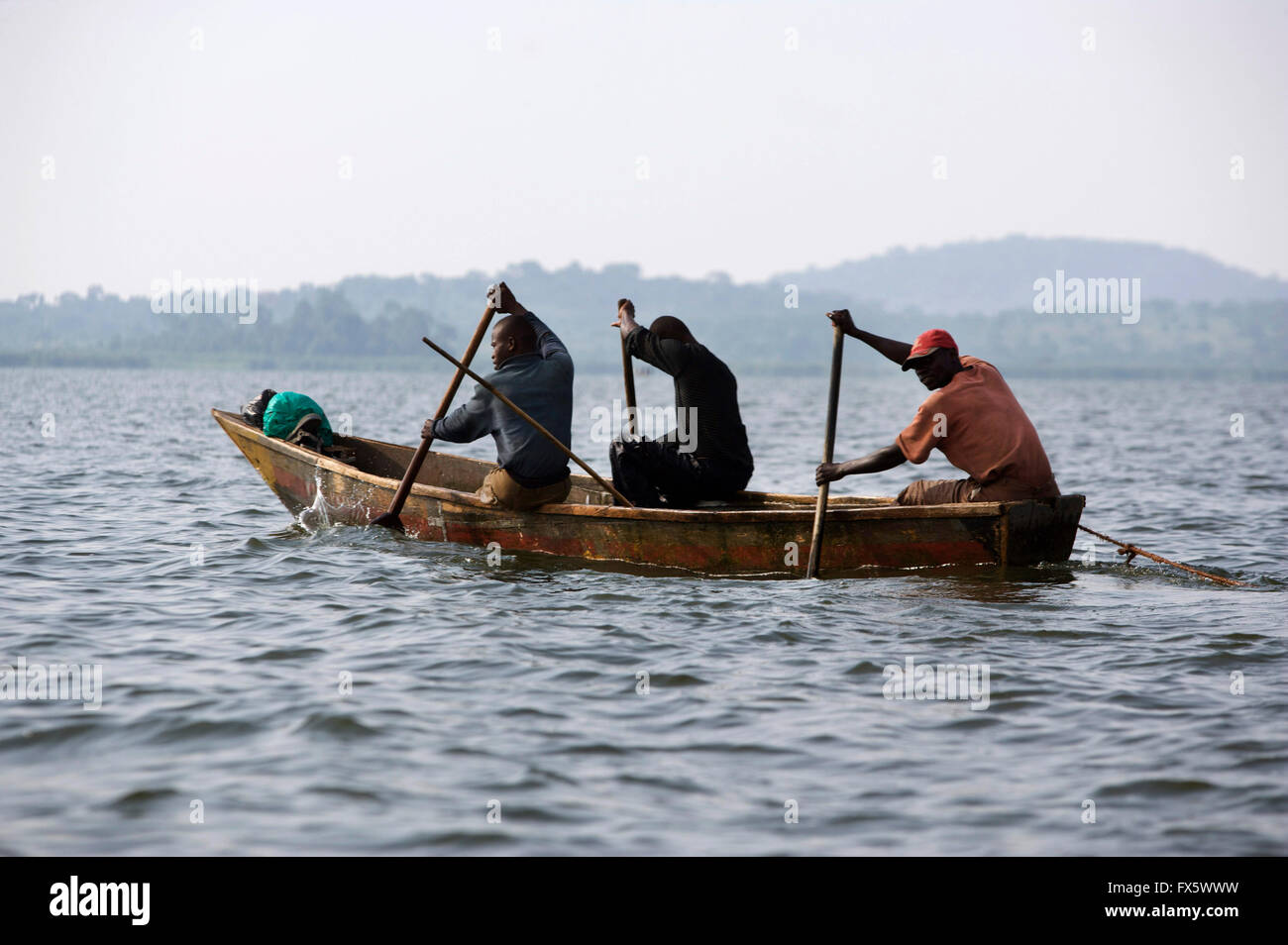 Men paddling in dug out canoe on lake Victoria, Uganda, Africa Stock