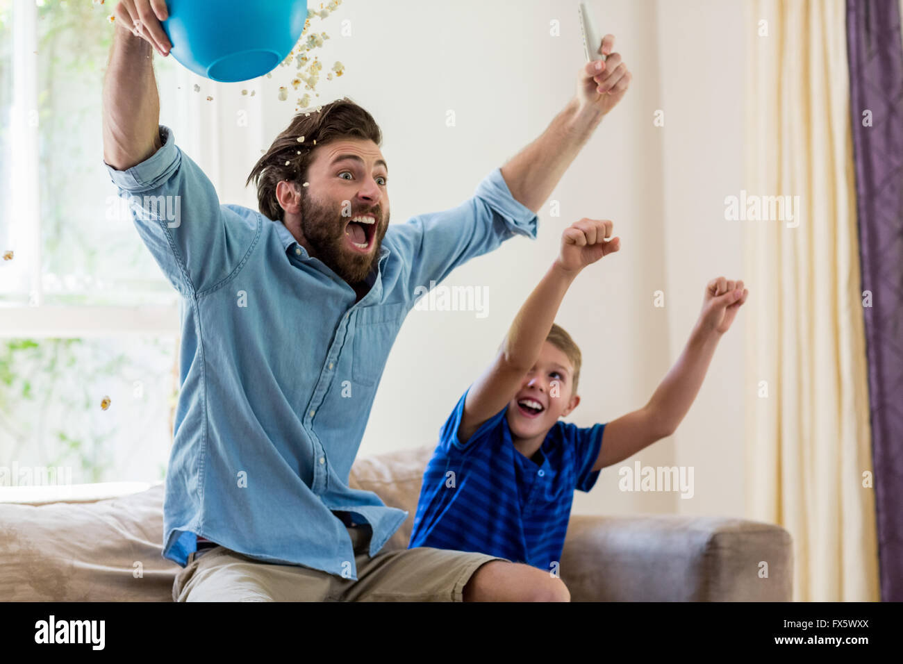 Excited father and son watching television Stock Photo