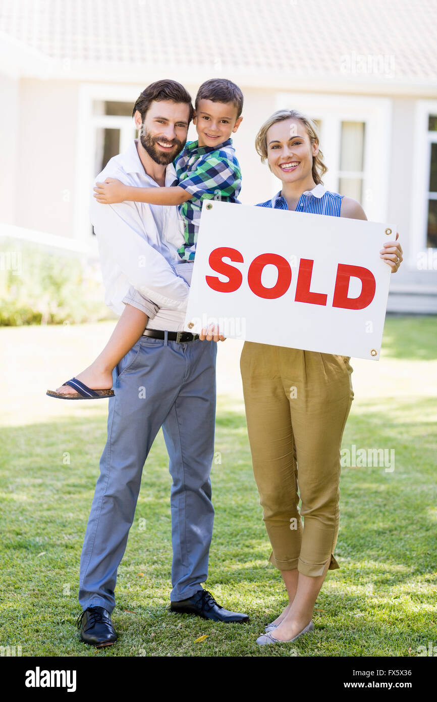Family standing outside home with sold sign Stock Photo - Alamy