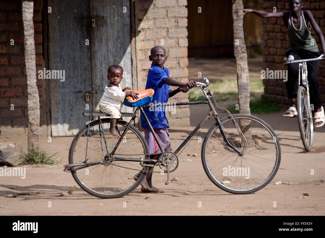 Children with bicycle in rural village in Uganda, Africa Stock Photo