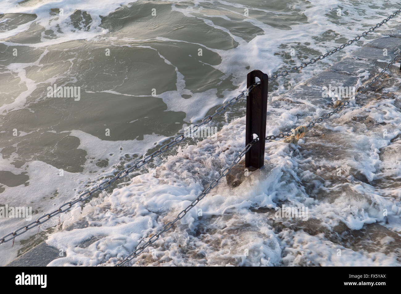 Waves breaking round metal post Stock Photo - Alamy