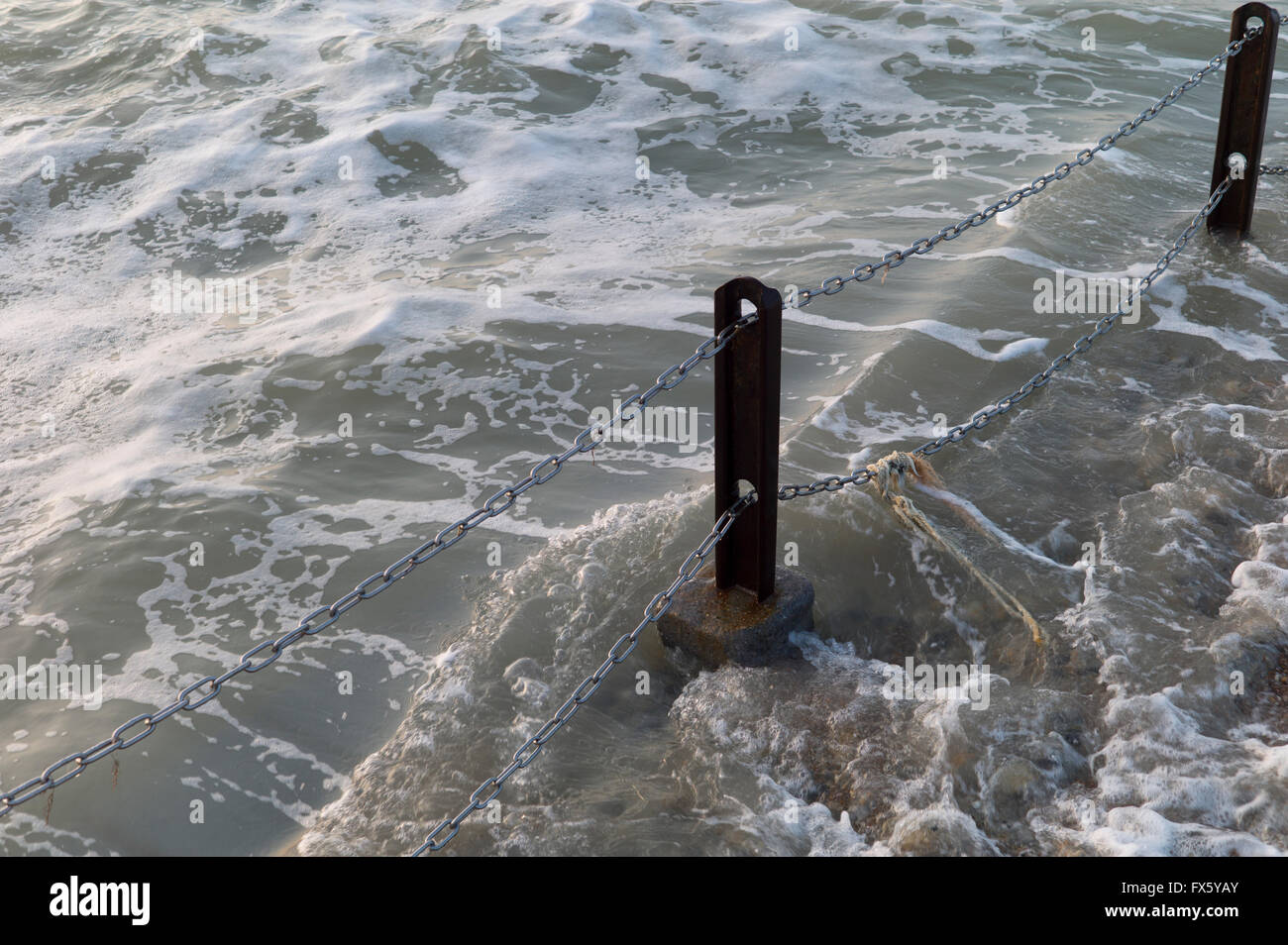 Waves breaking round metal post Stock Photo - Alamy