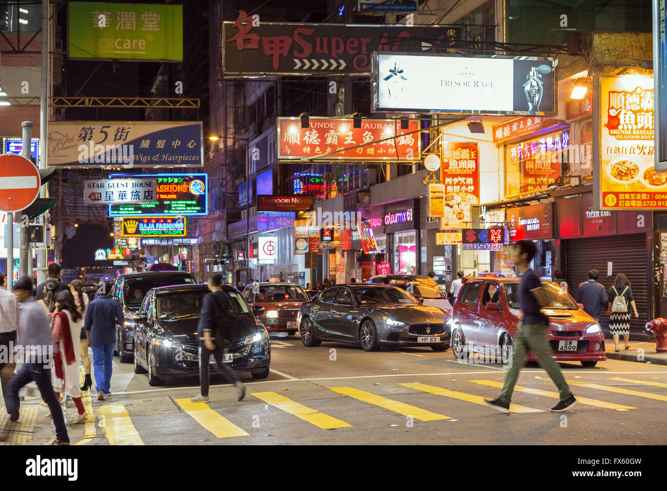 People and cars at a street in Kowloon, Hong Kong, China, at night ...