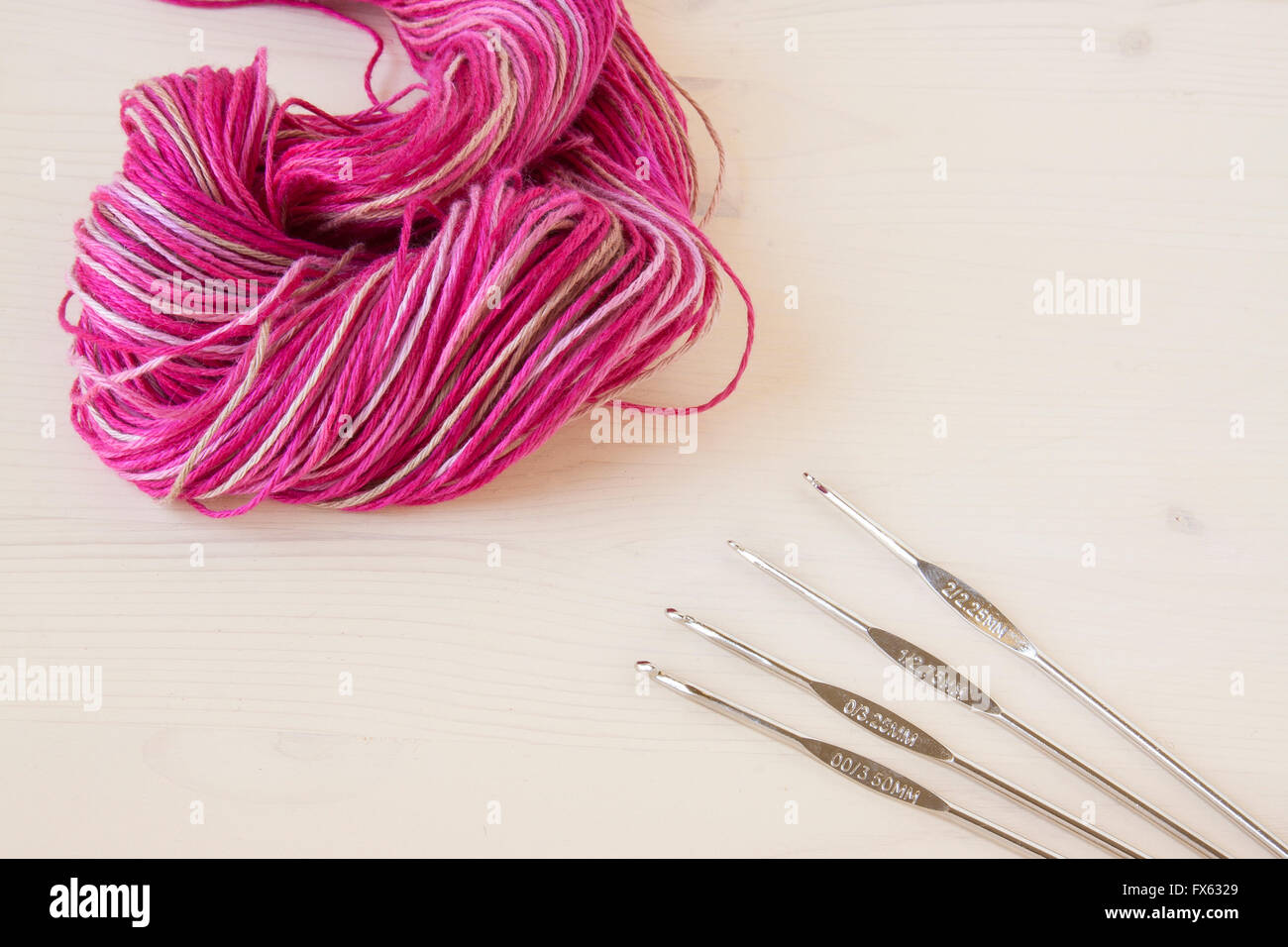 Crochet hooks and a skein of yarn on a wooden background. Stock Photo