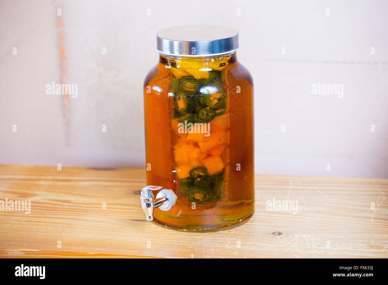 Tequila infused with jalapeno peppers in a tea jar at a restaurant bar. Stock Photo