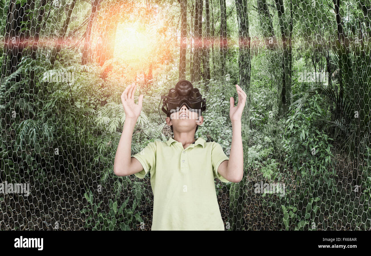 Mixed race boy wearing virtual reality goggles in remote forest Stock Photo