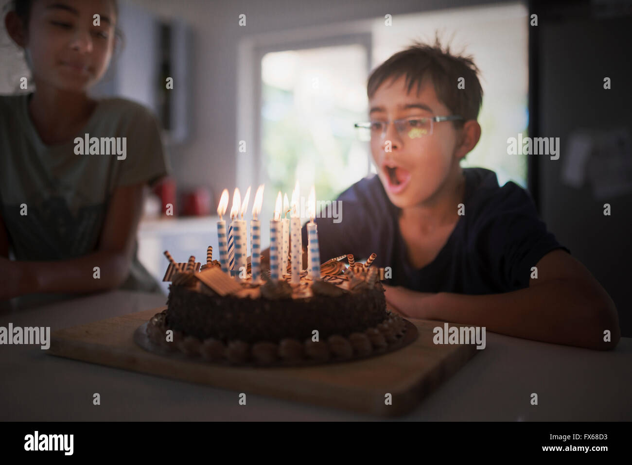 Mixed race boy blowing birthday candles Stock Photo