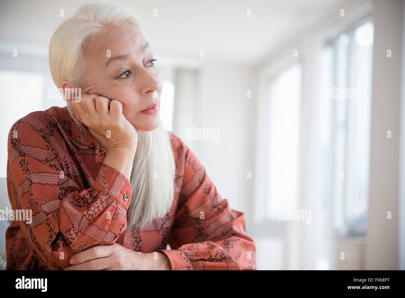 Caucasian woman sitting with chin in hand Stock Photo