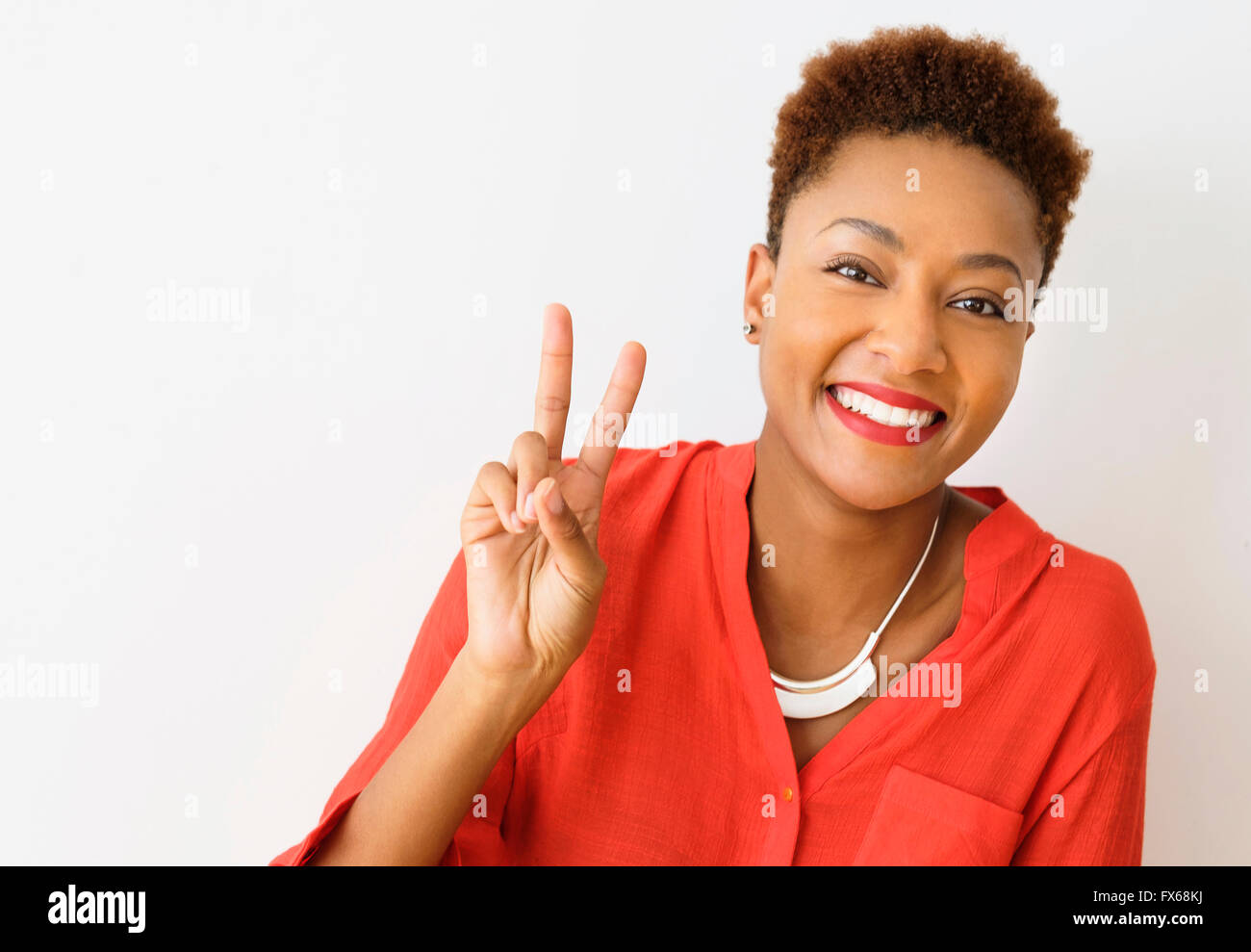 Mixed race woman making peace sign Stock Photo