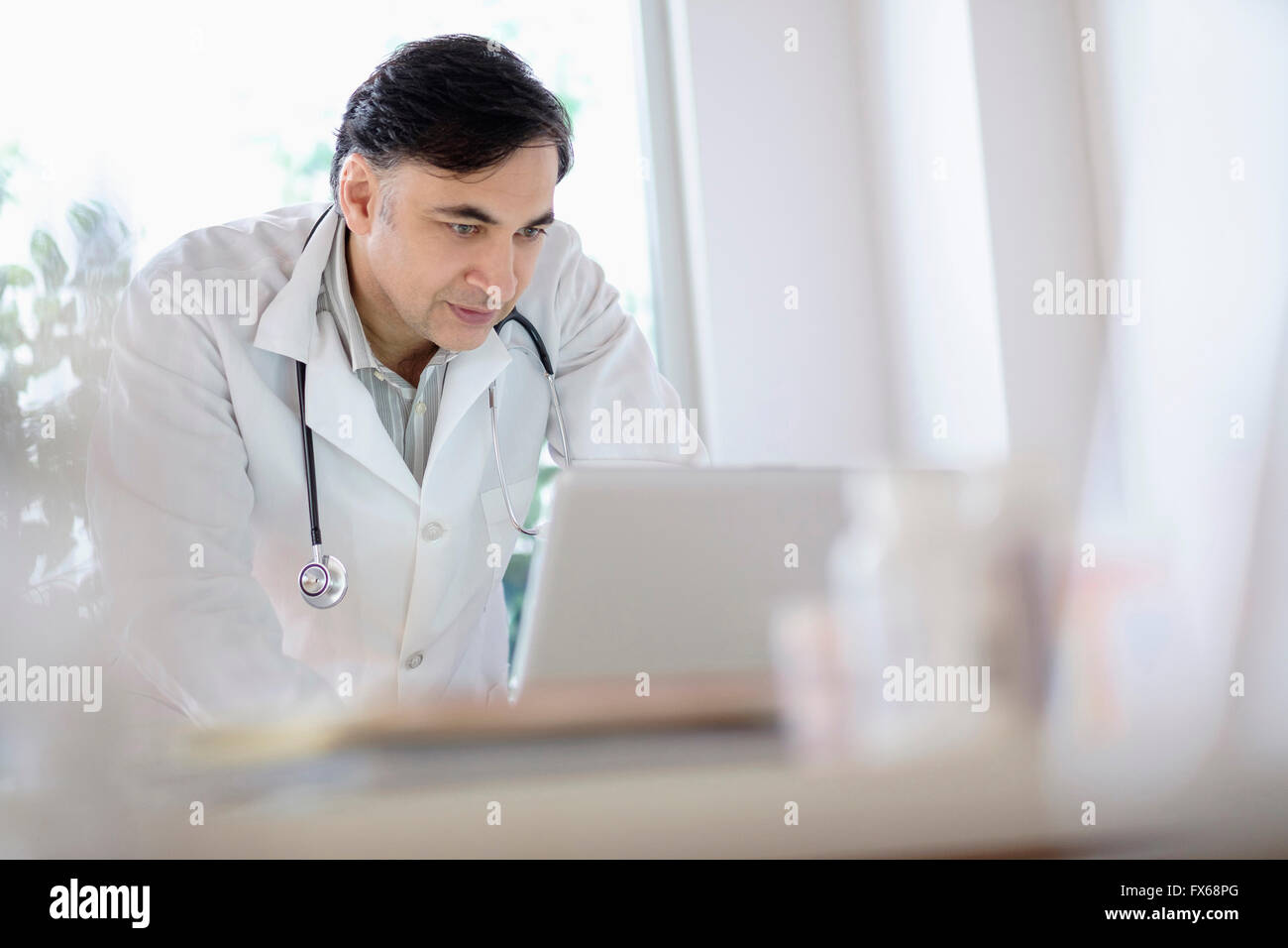 Mixed race doctor working on laptop Stock Photo