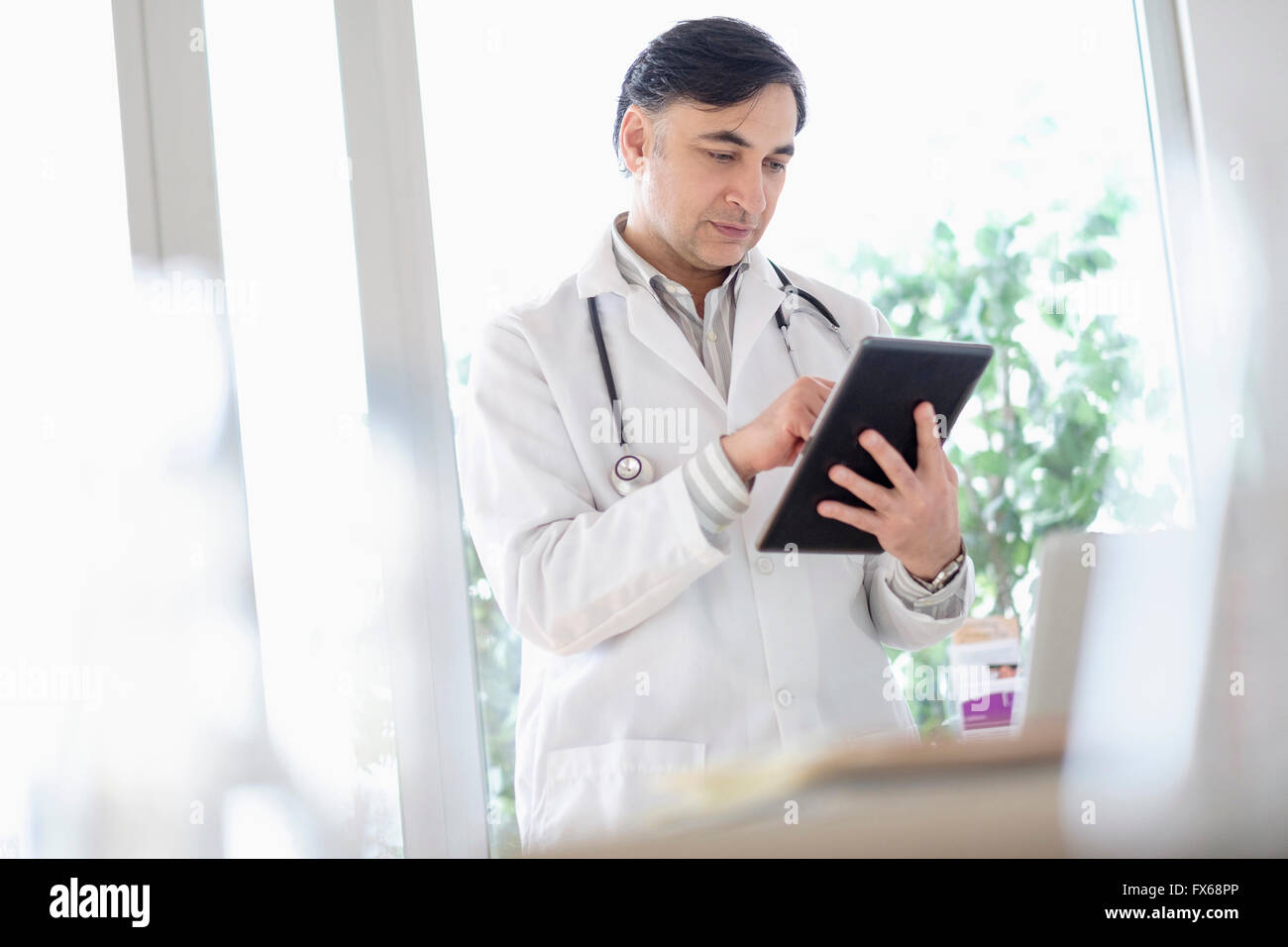 Mixed race doctor using digital tablet Stock Photo