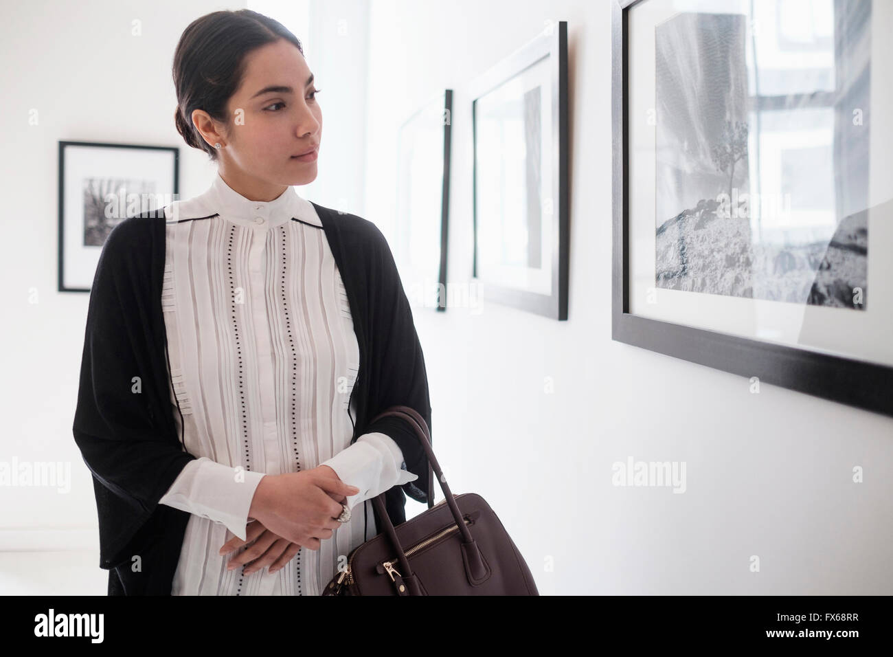 Hispanic woman admiring art in gallery Stock Photo