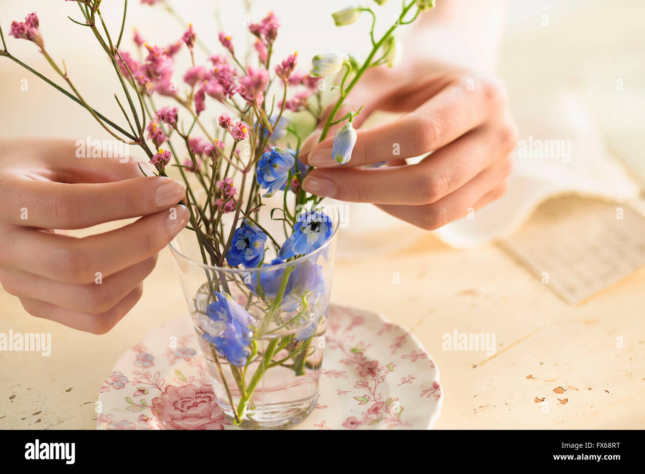 Hispanic woman arranging flowers in glass cup Stock Photo