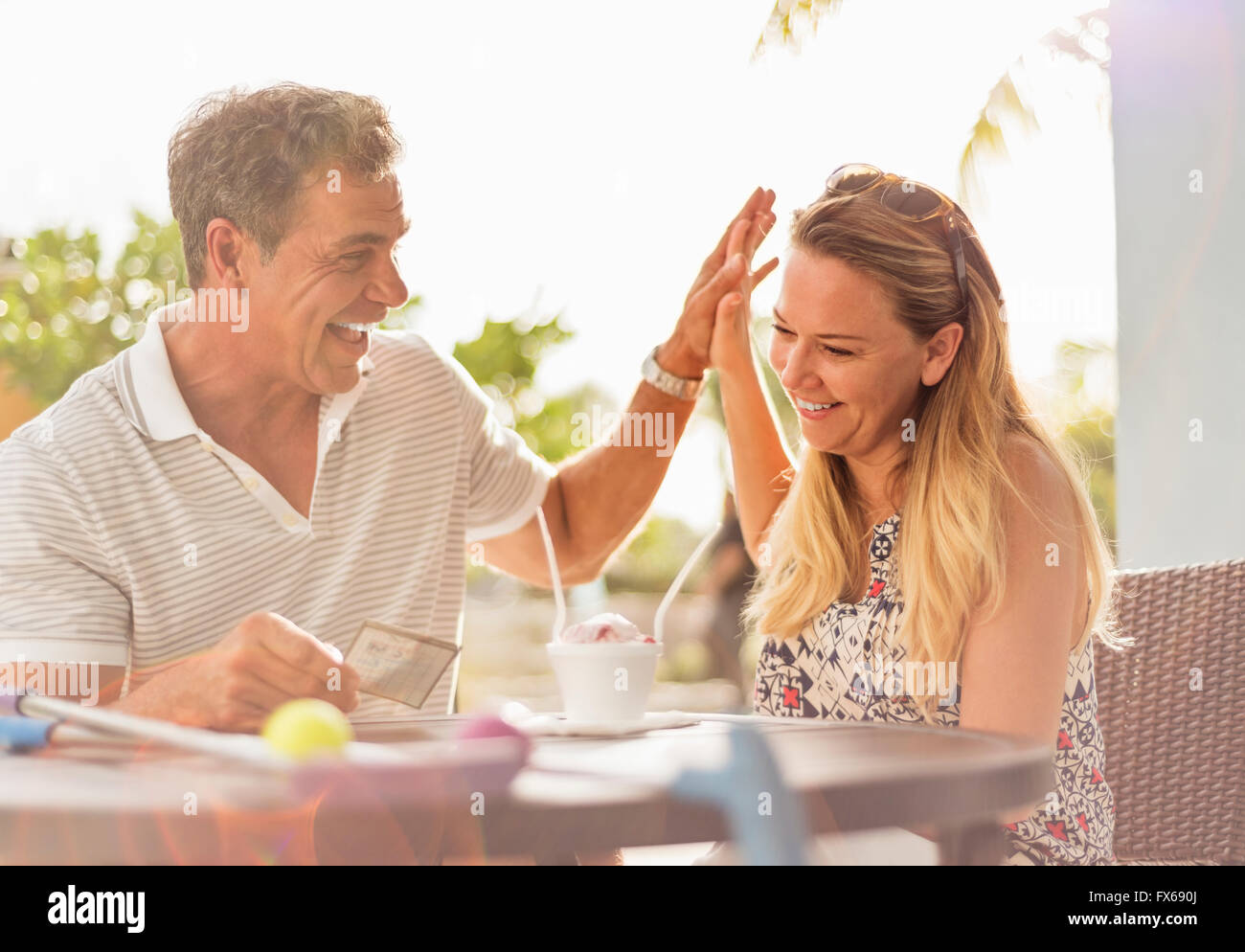Caucasian couple high-fiving at outdoor table Stock Photo