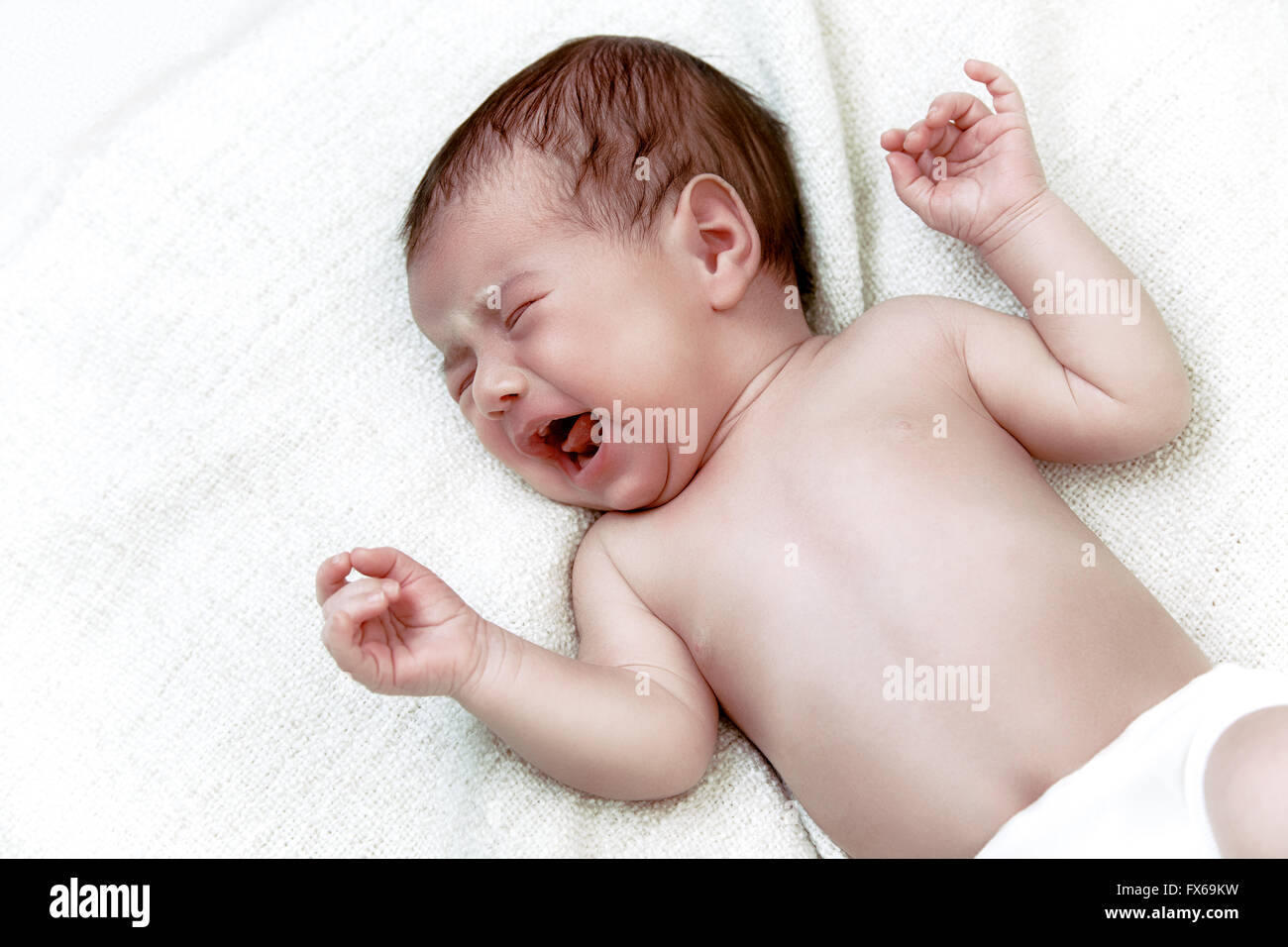 Newborn baby crying in white bad Stock Photo
