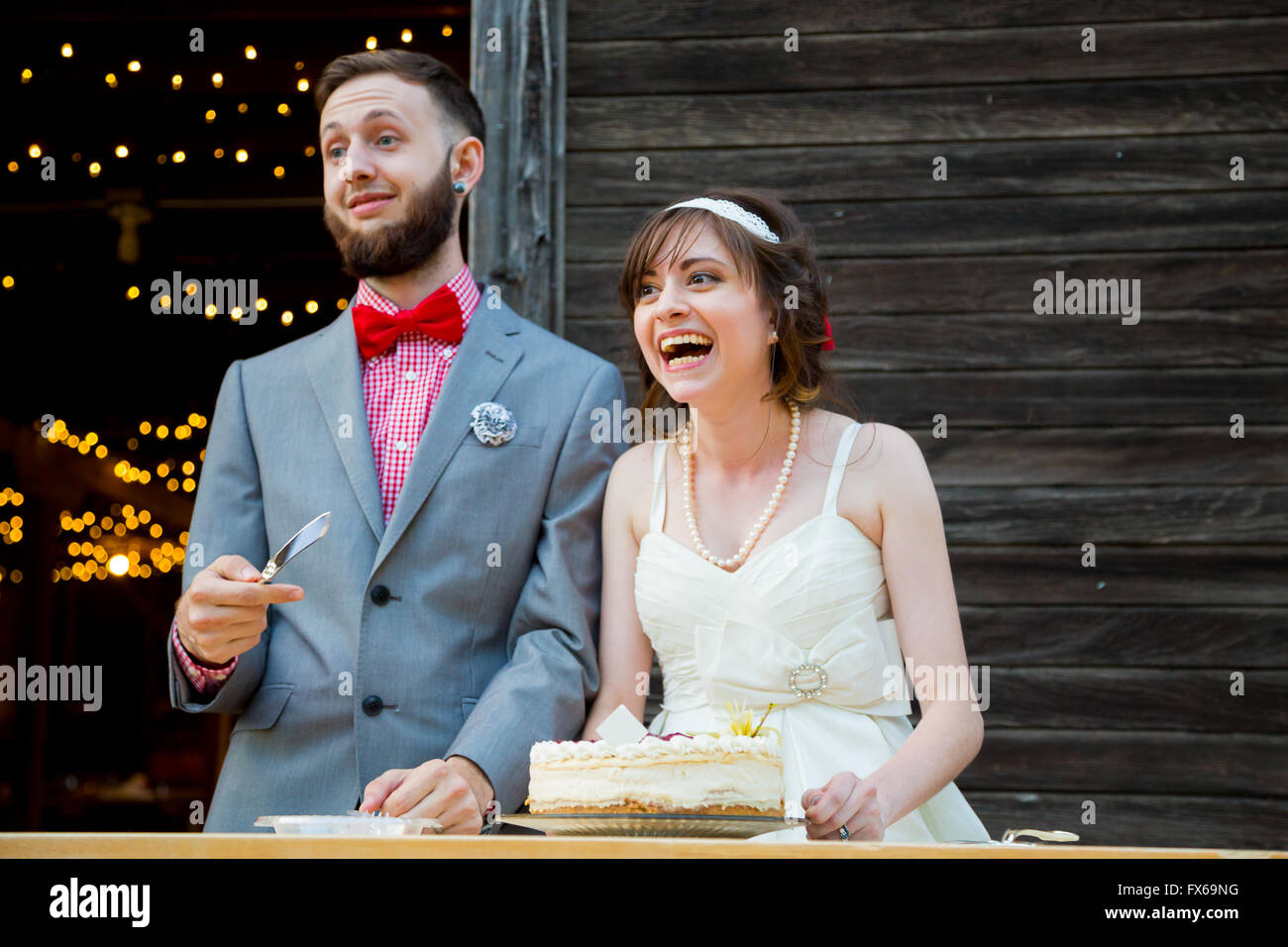 Bride and groom cut the cake and feed each other on their wedding day at the reception. Stock Photo