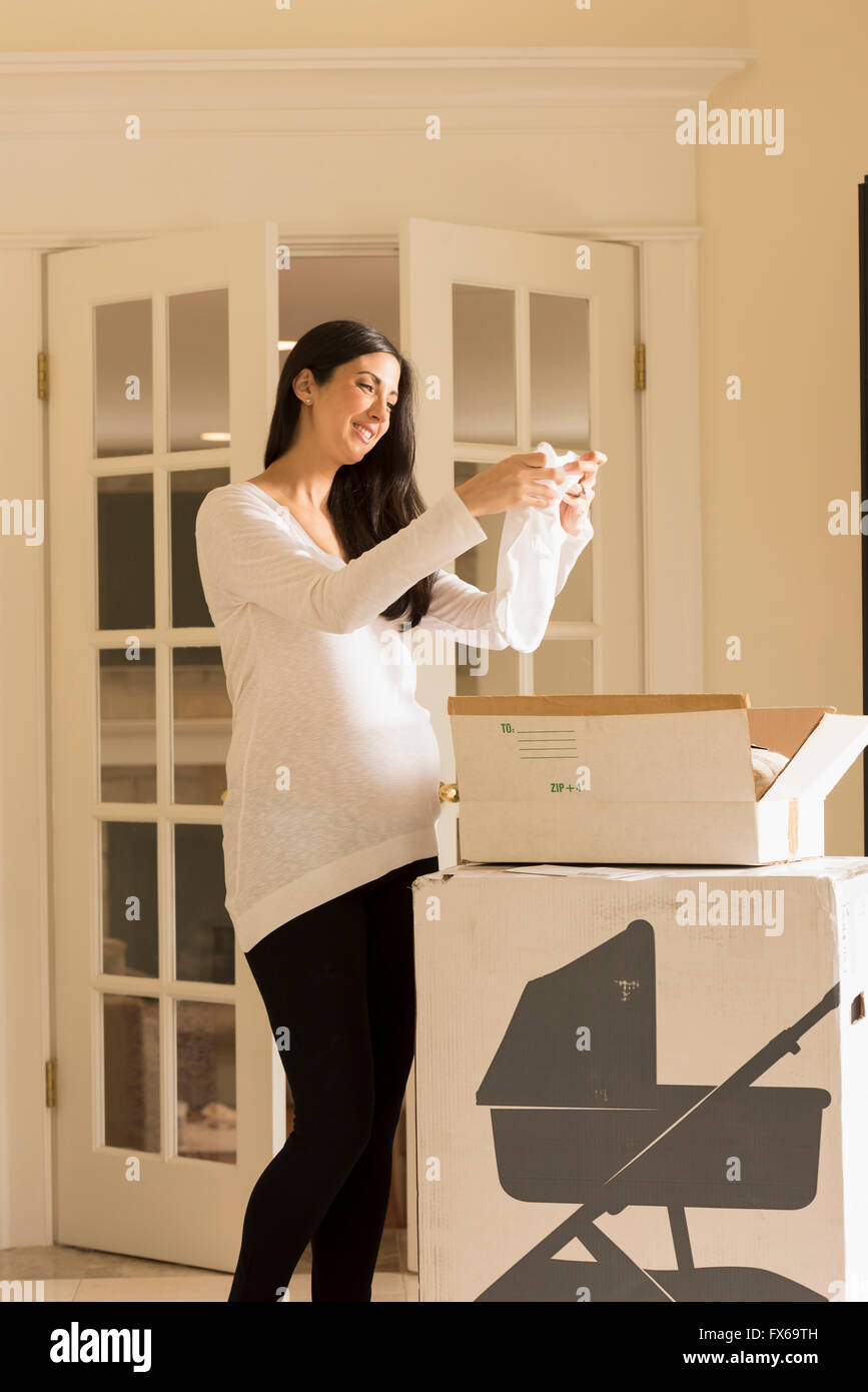 Pregnant Caucasian woman admiring baby clothing Stock Photo