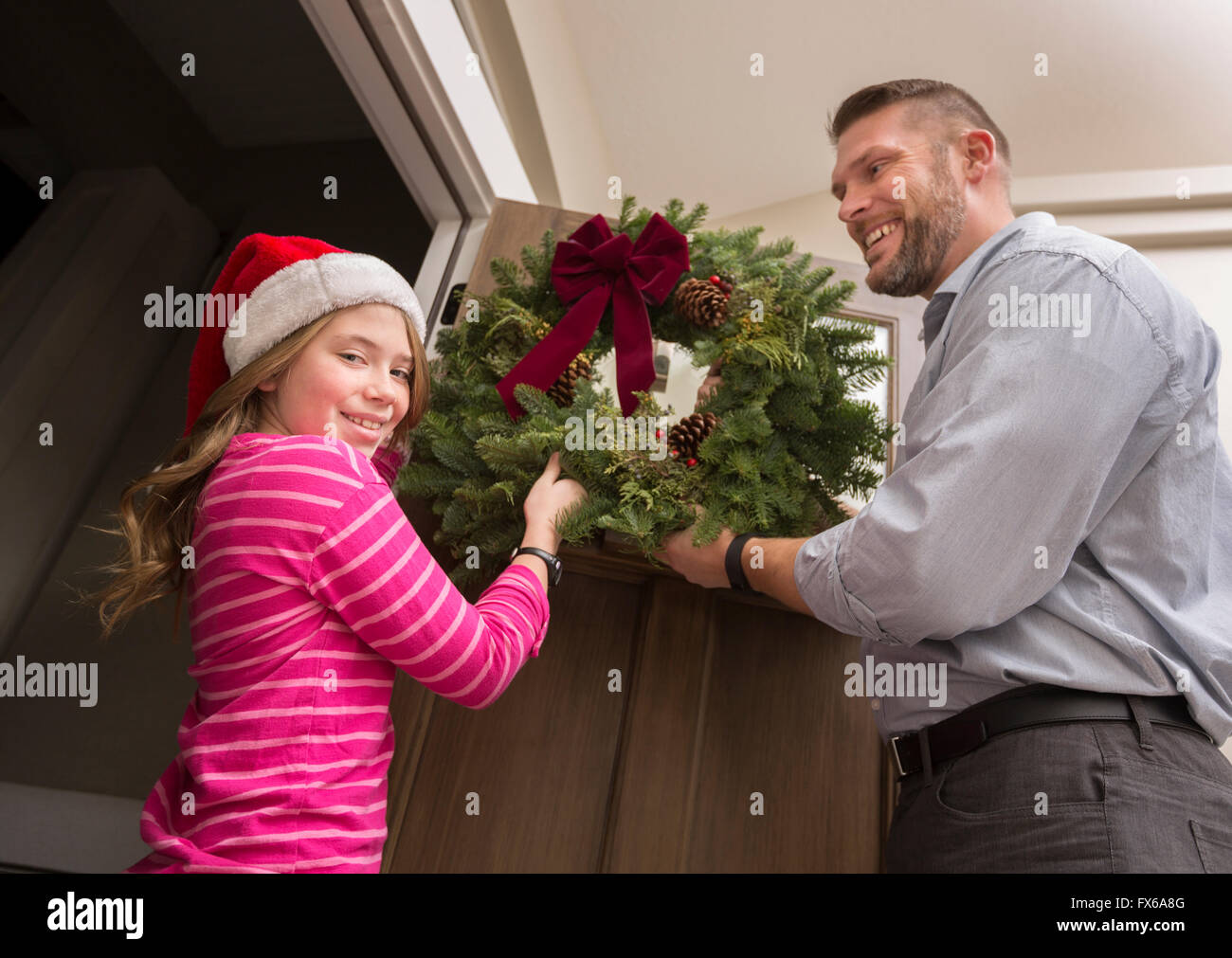 Caucasian father and daughter hanging Christmas wreath Stock Photo