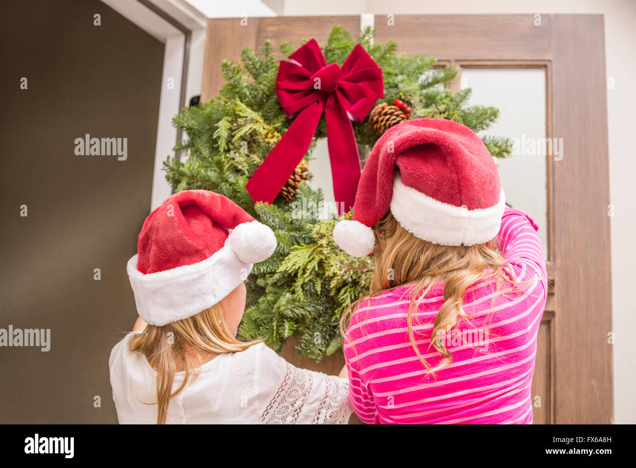 Caucasian girls hanging Christmas wreath Stock Photo
