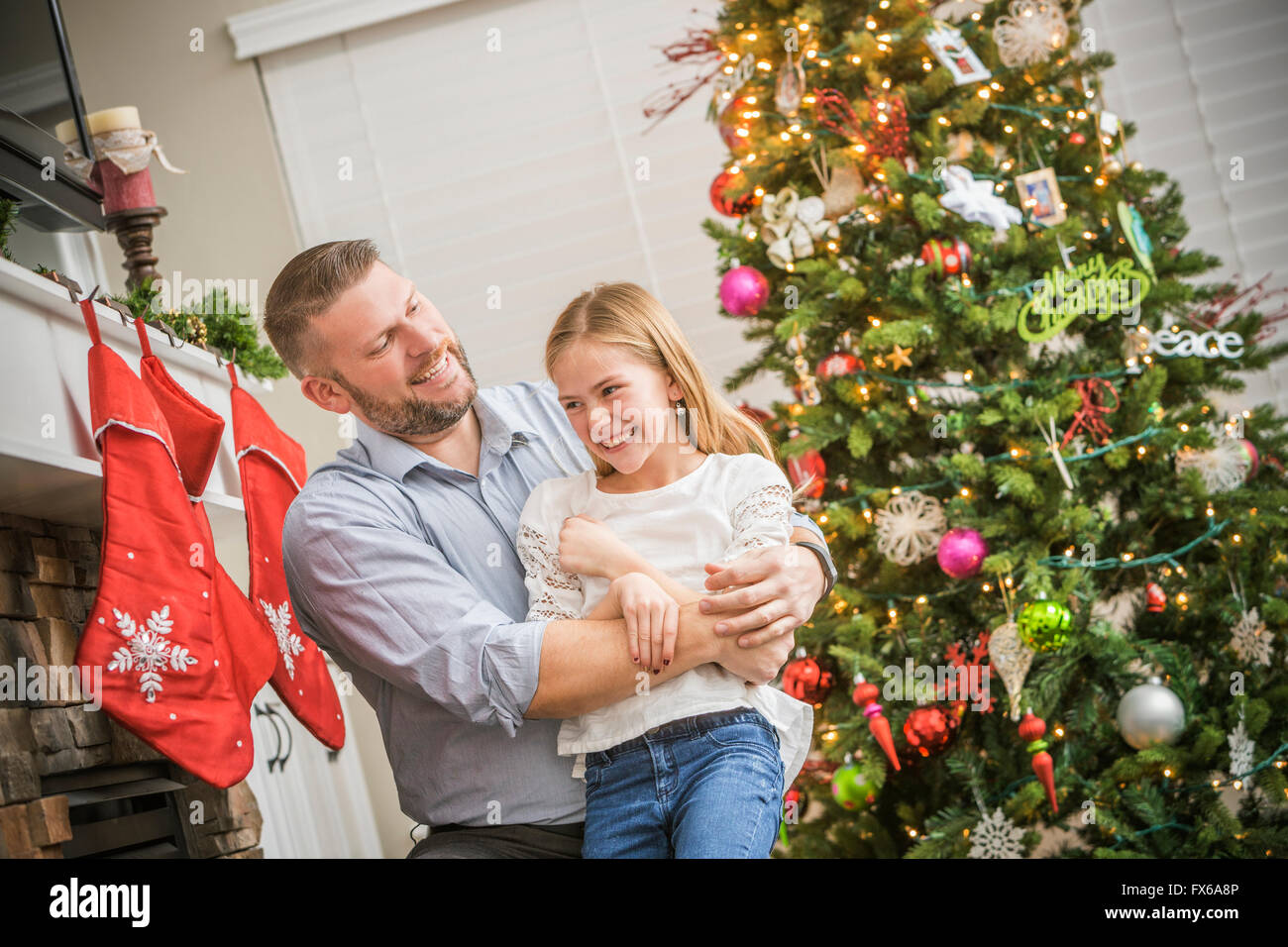 Caucasian father and daughter hugging near Christmas tree Stock Photo