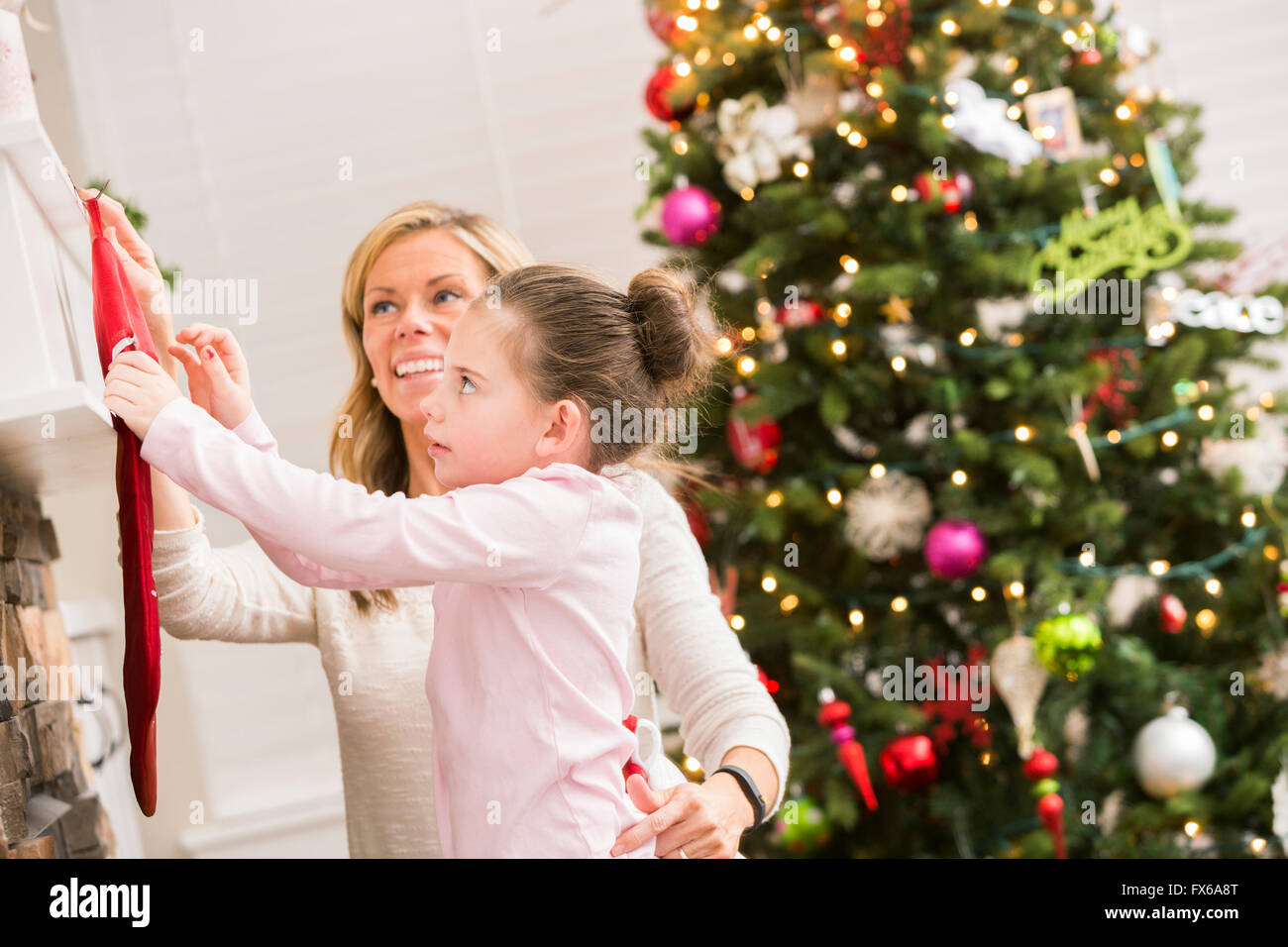 Caucasian mother and daughter hanging Christmas stockings Stock Photo