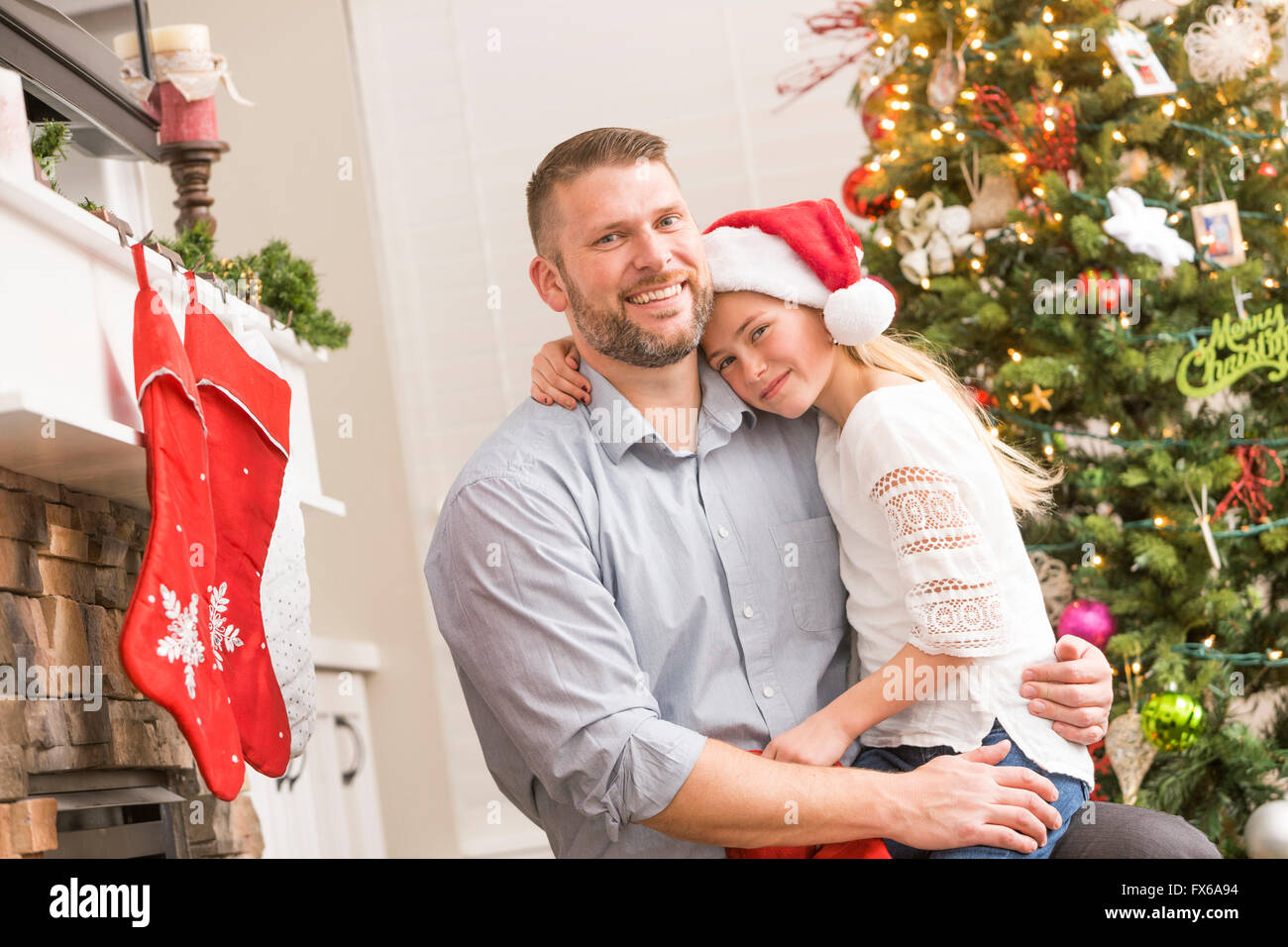 Caucasian father and daughter hugging near Christmas tree Stock Photo
