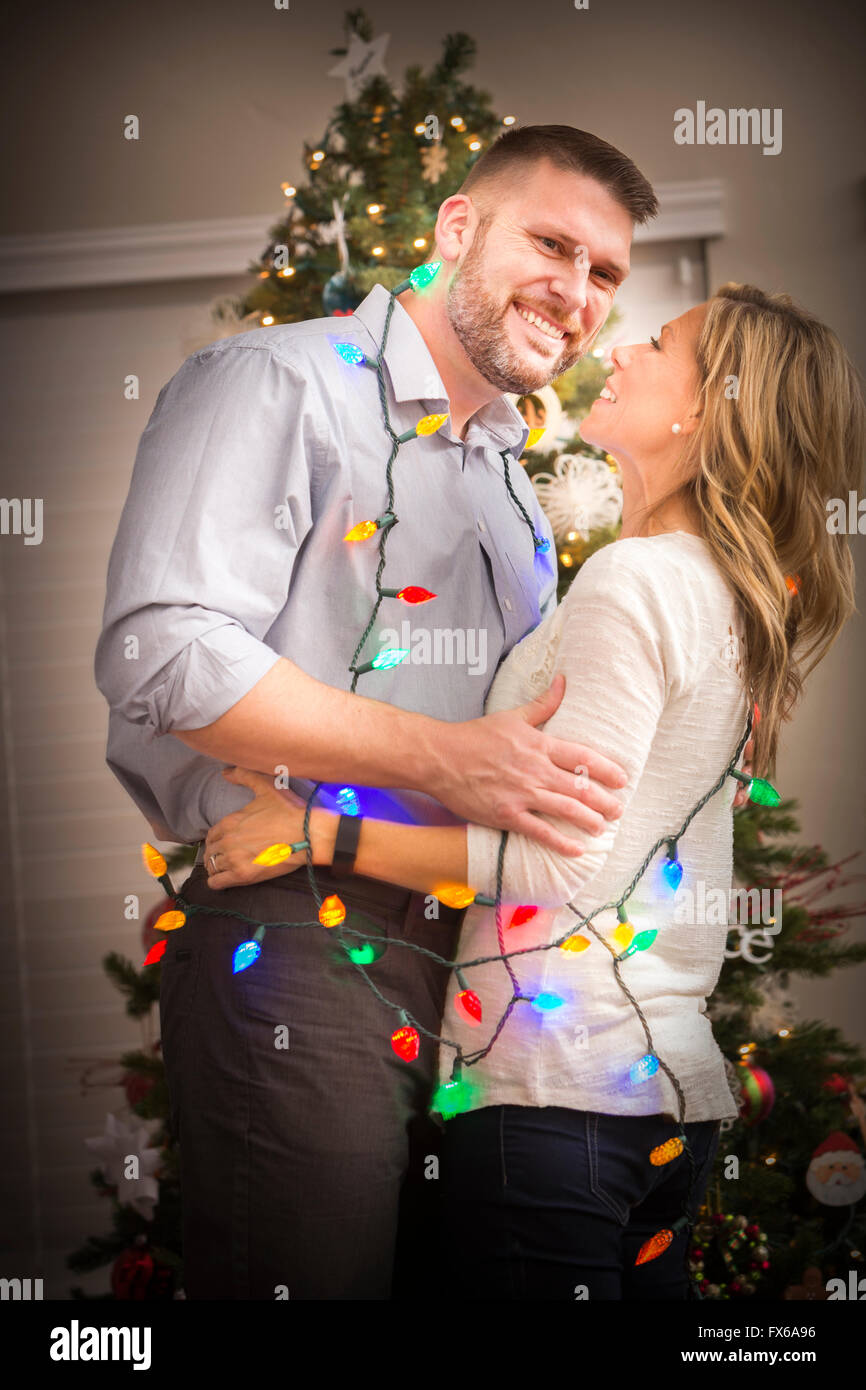 Caucasian couple wrapped in Christmas lights Stock Photo