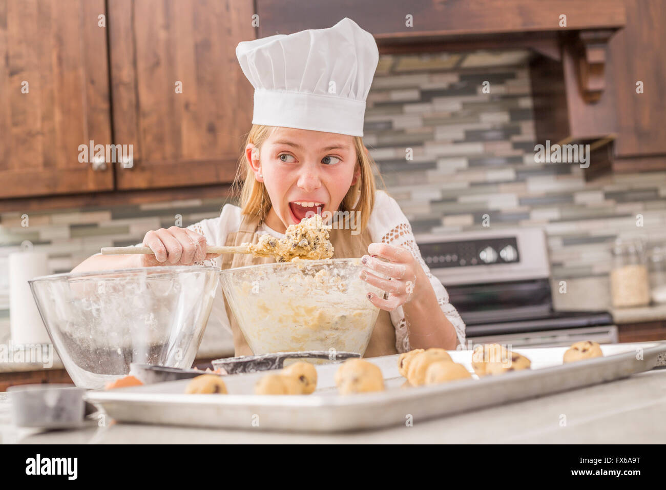 Caucasian girl tasting cookie dough in kitchen Stock Photo