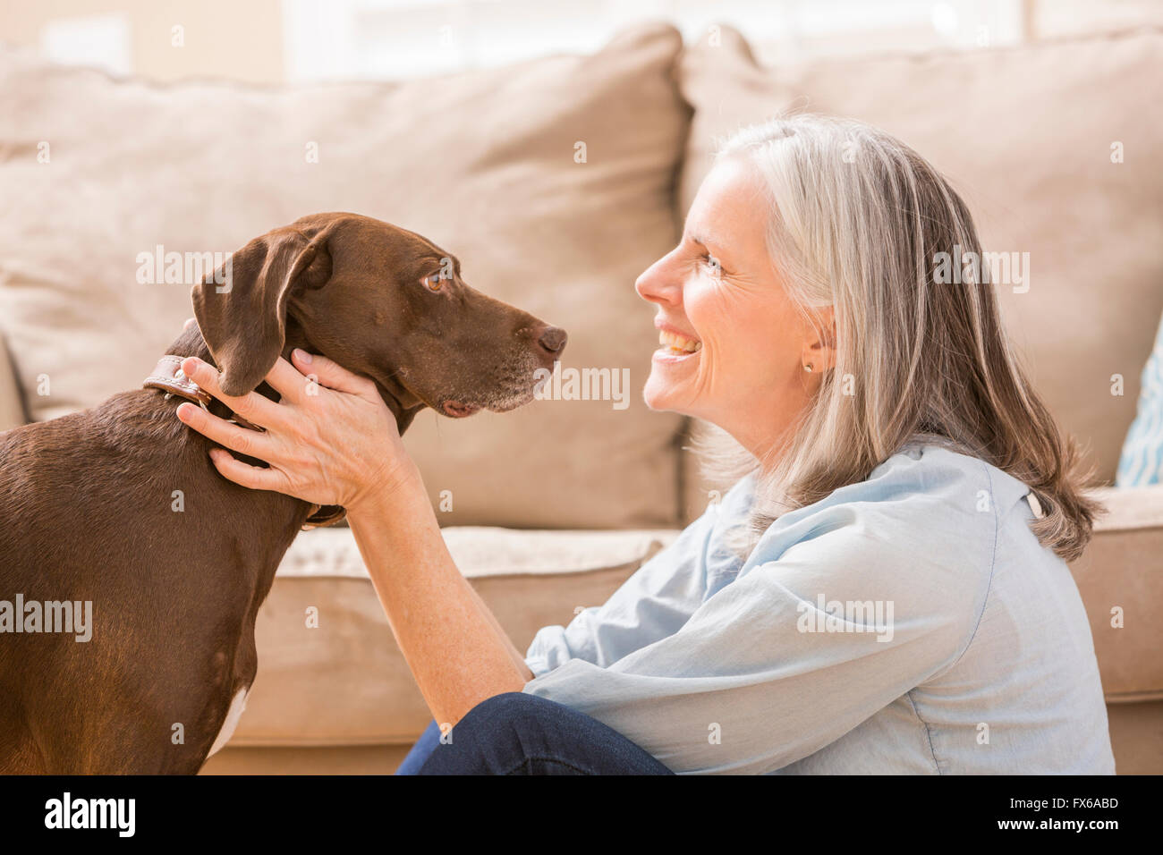Caucasian woman hugging dog in living room Stock Photo