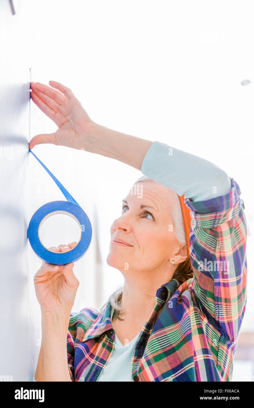 Caucasian woman taping off painting area Stock Photo