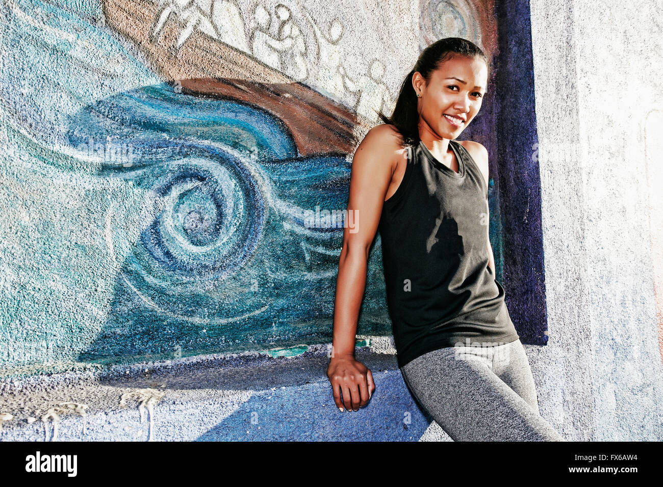 Mixed race athlete sitting on mural wall Stock Photo Alamy