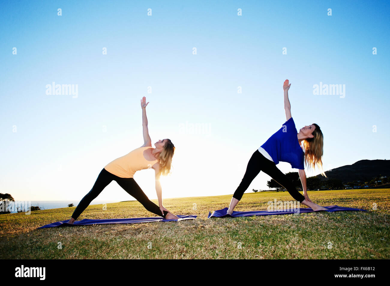 Caucasian women practicing yoga in field Stock Photo