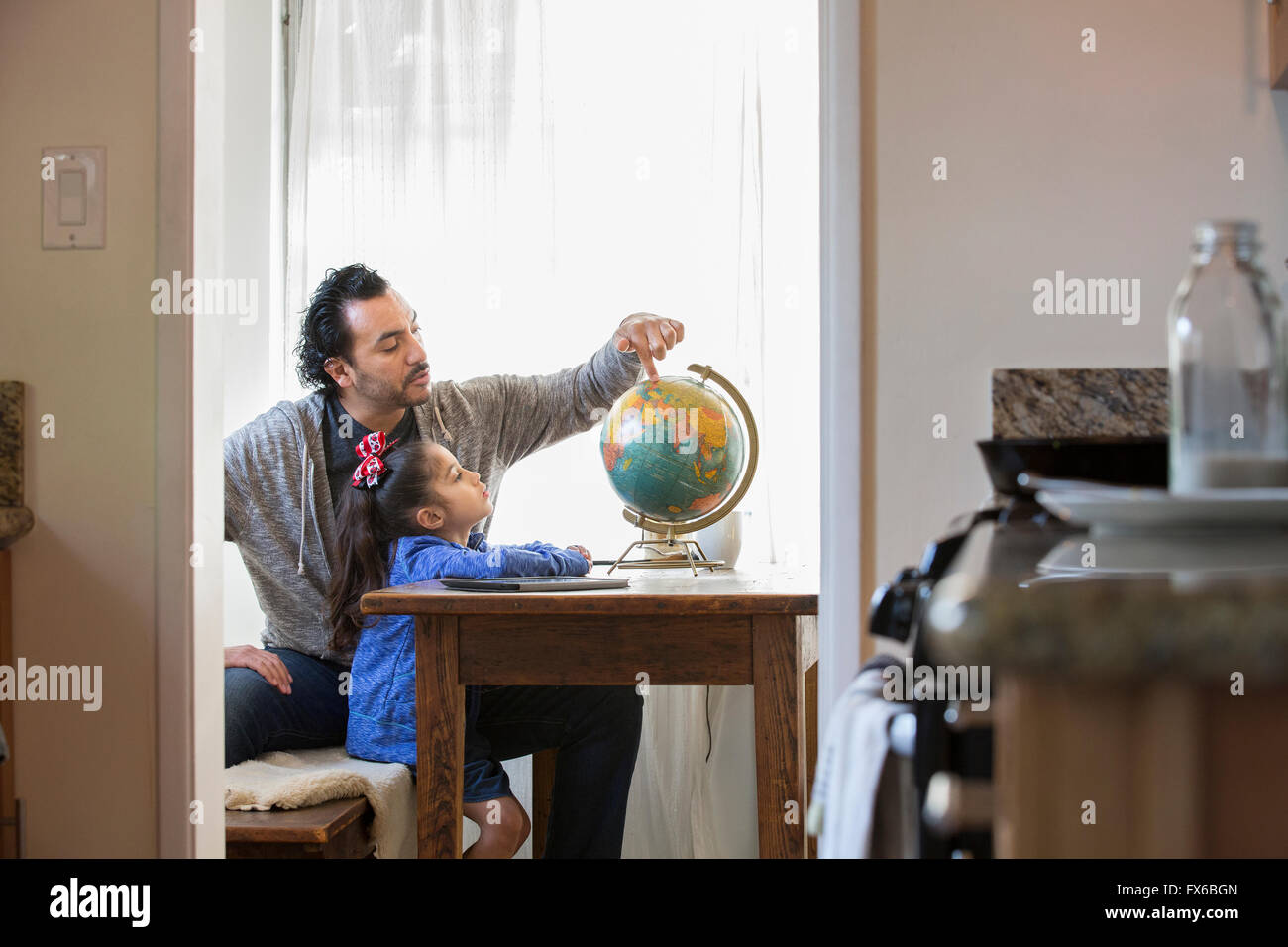 Hispanic father and daughter examining globe Stock Photo