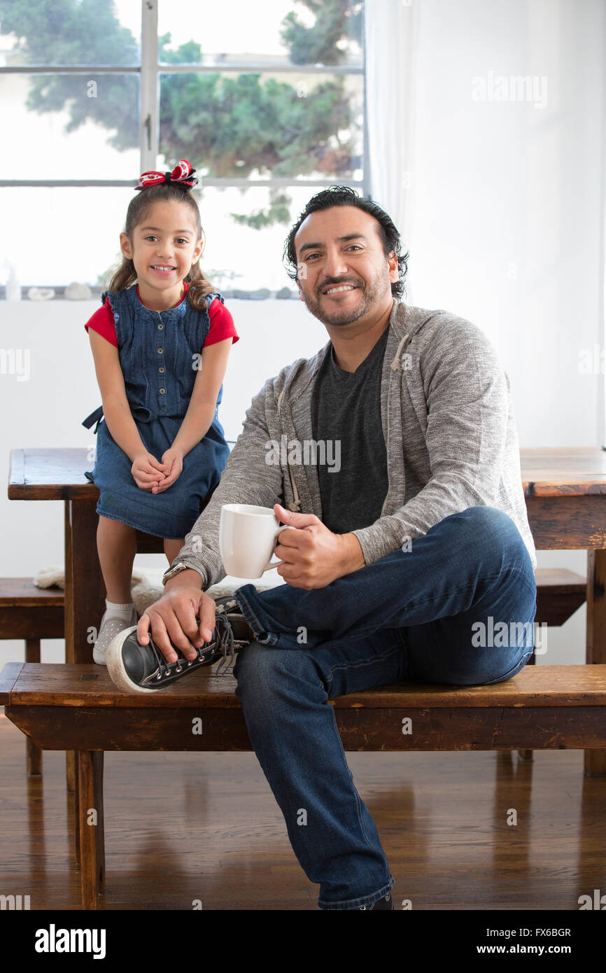 Hispanic father and daughter smiling at table Stock Photo