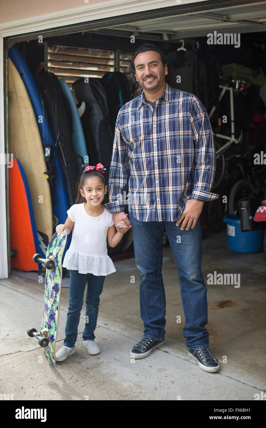 Hispanic father and daughter smiling in garage Stock Photo