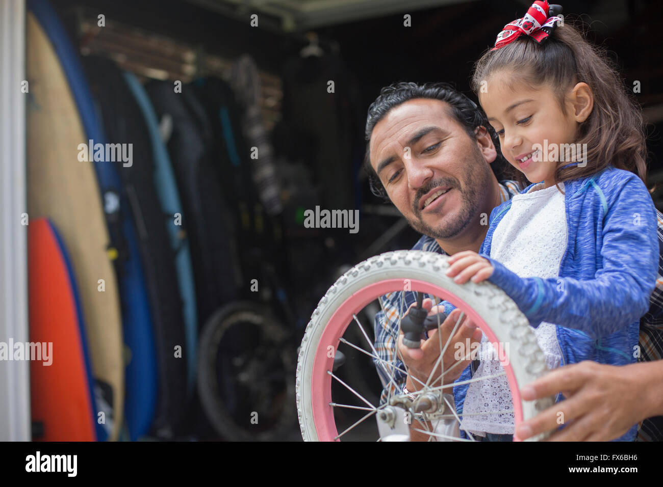 Hispanic father teaching daughter to repair bicycle Stock Photo