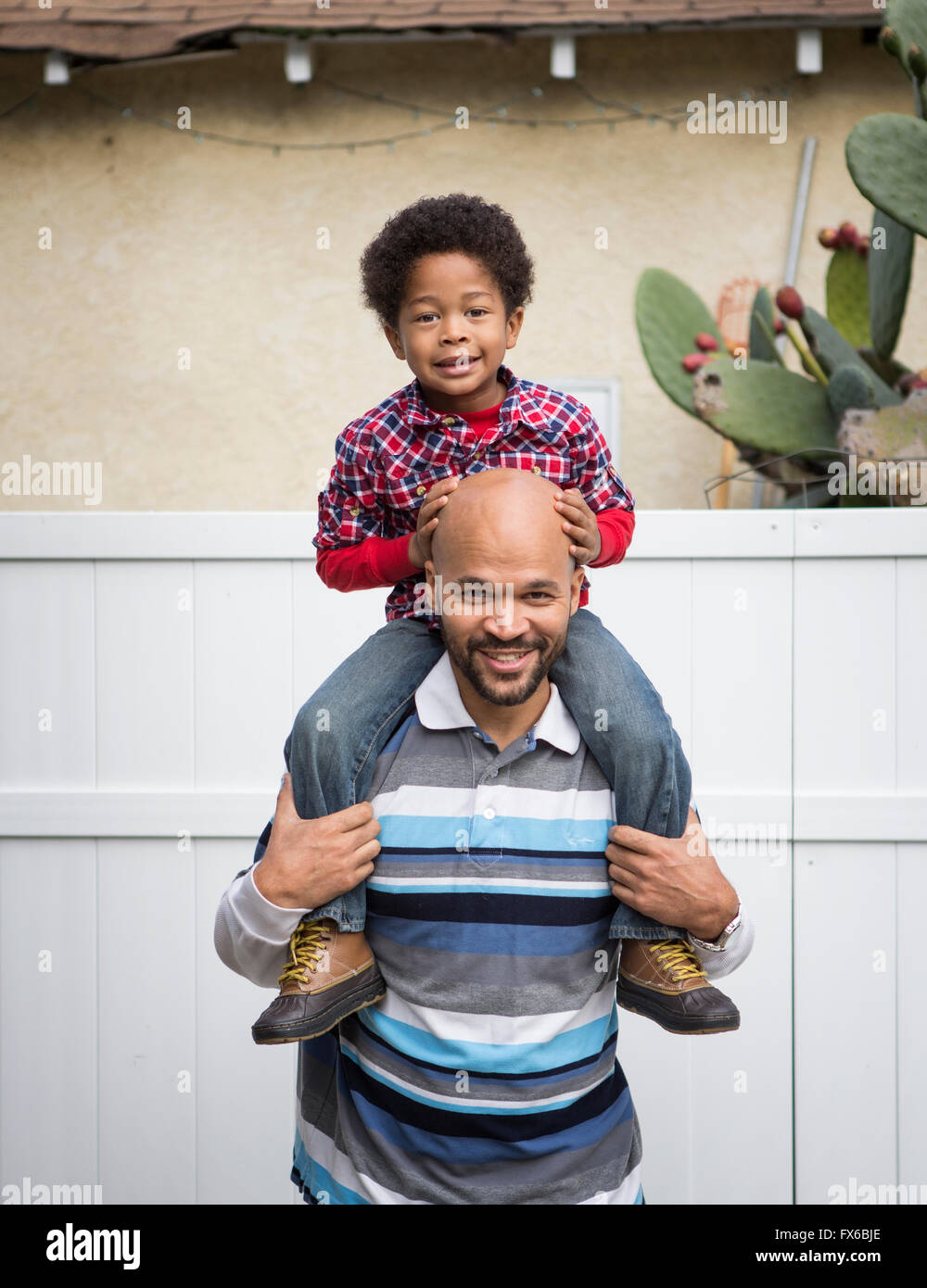 Mixed race father carrying son on shoulders Stock Photo