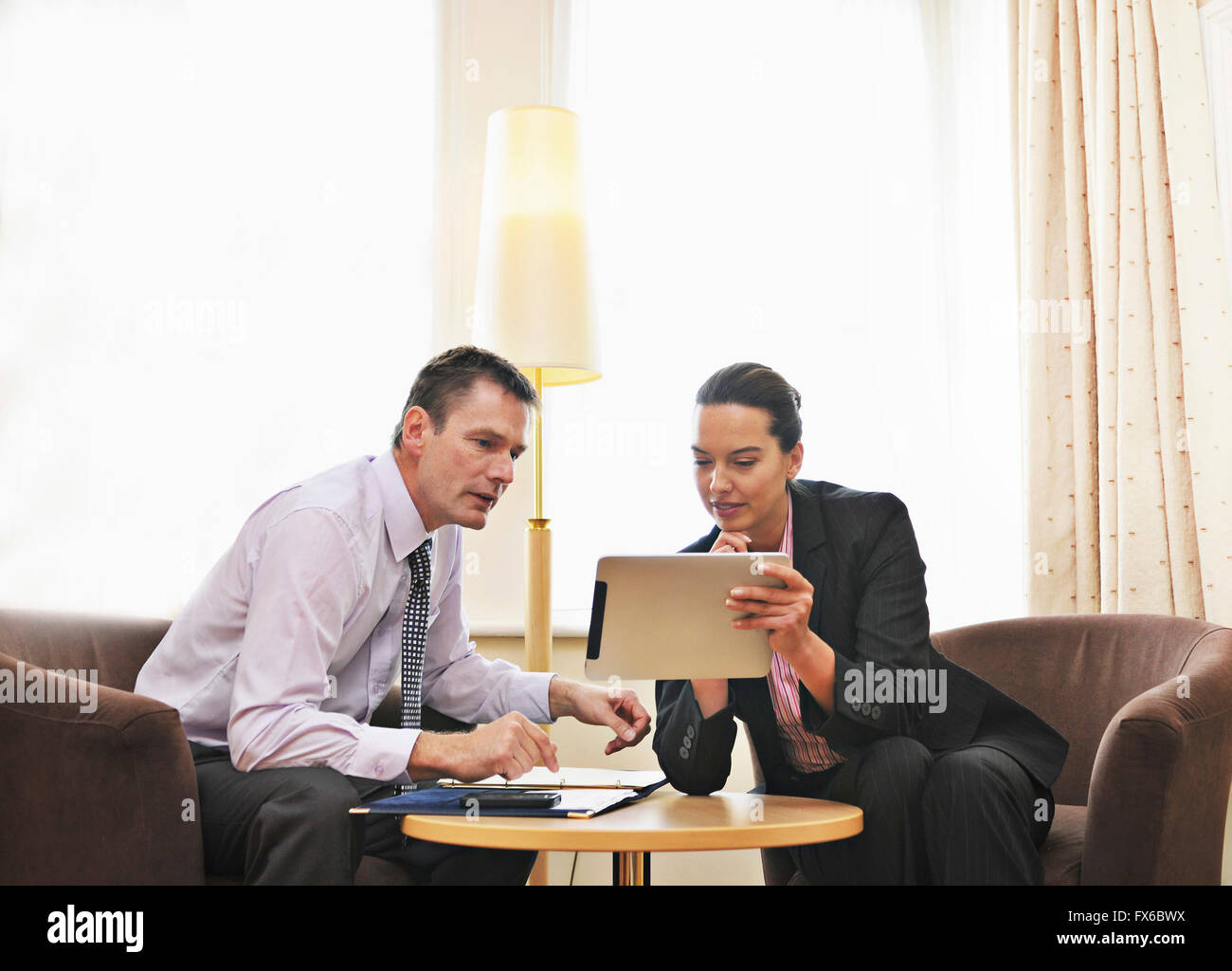 Caucasian business people using digital tablet in lounge Stock Photo